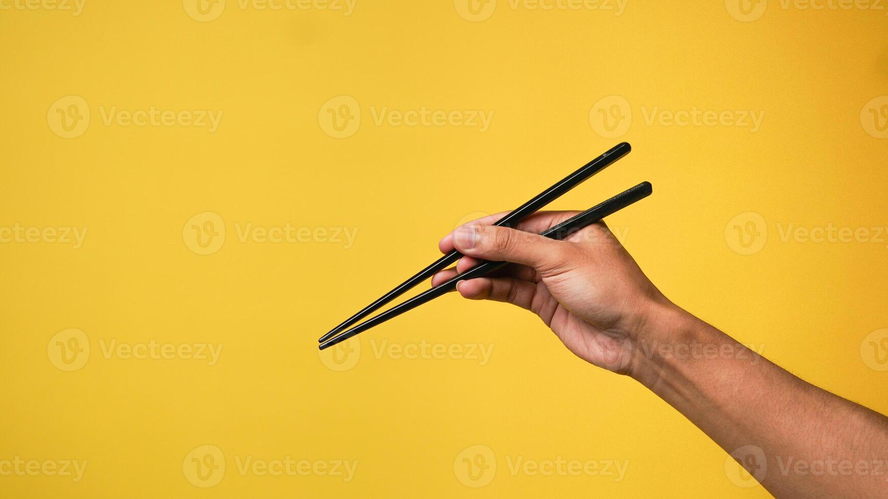 Man's hand pointing finger at camera on yellow background photo