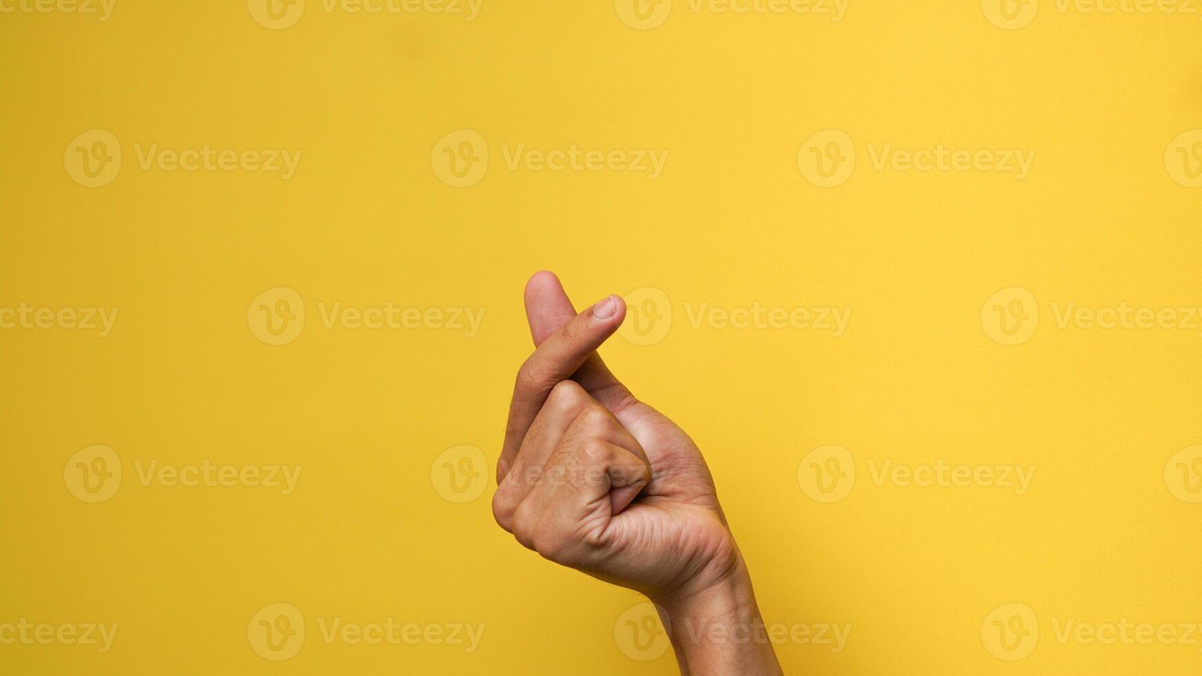 Men's hands give a love gesture on a yellow background photo