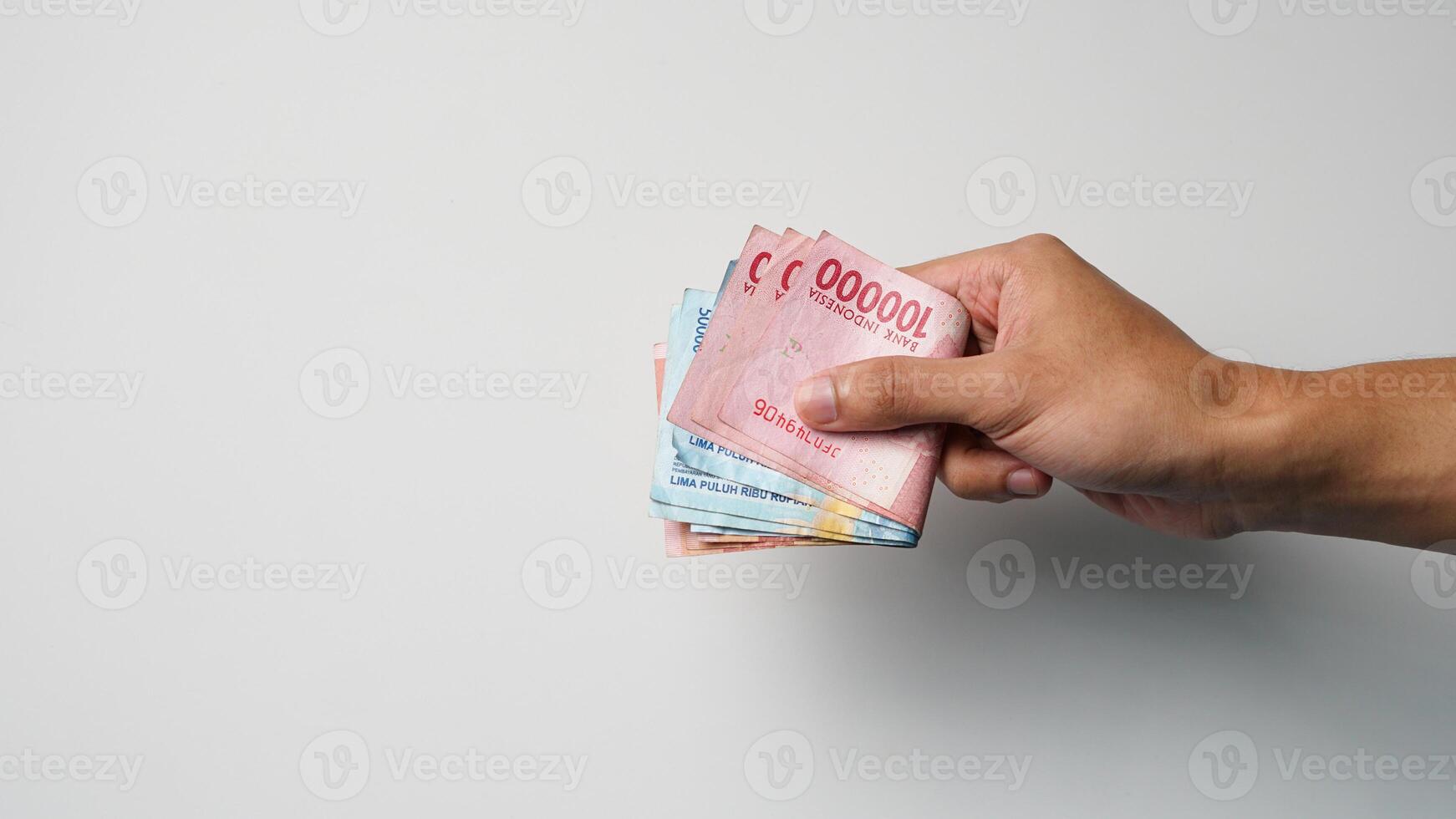 Man's hand holding a wad of Indonesian money to pay cash photo