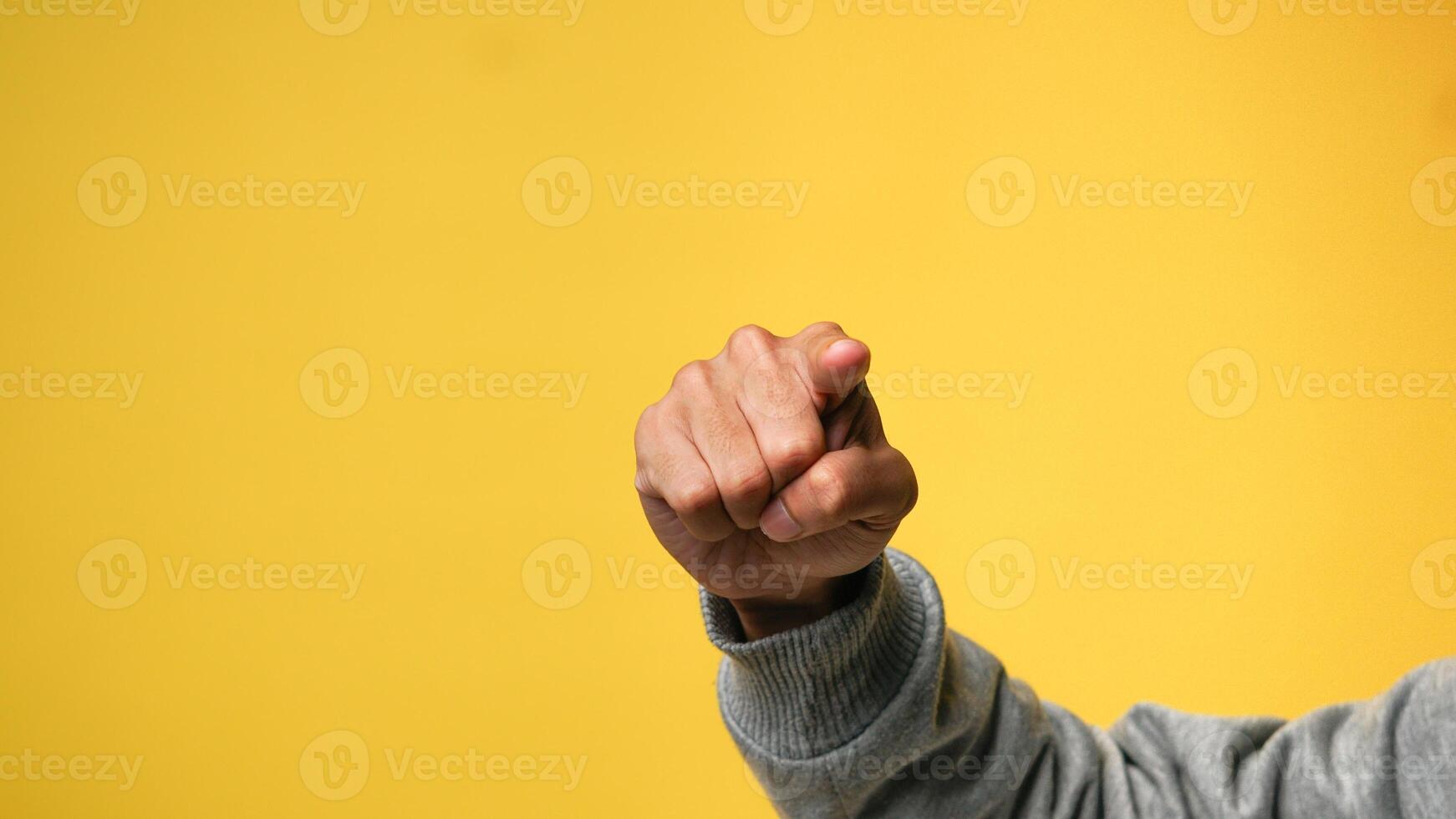 Man's hand pointing finger at camera on yellow background photo