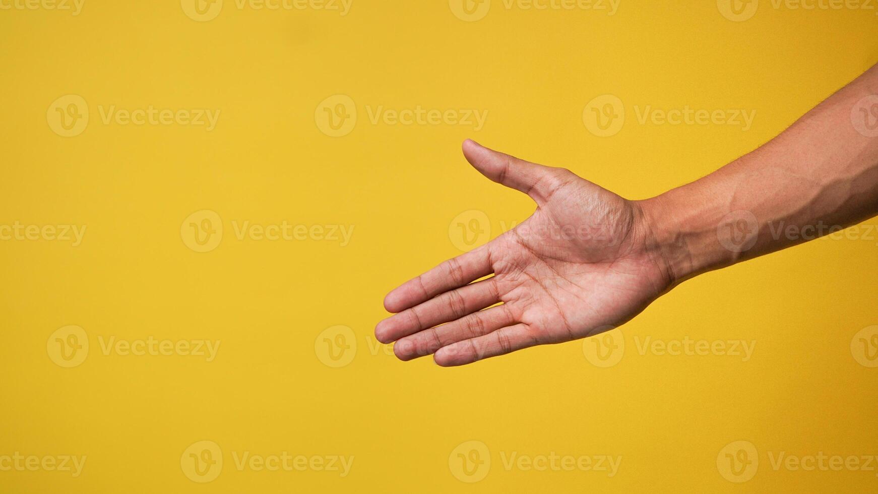 Man's hand pointing finger at camera on yellow background photo