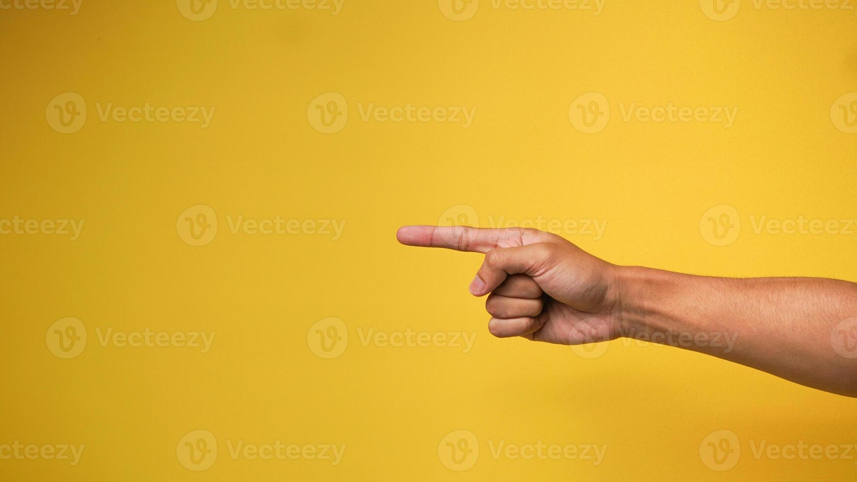 Man's hand with pointing hand gesture on yellow background photo