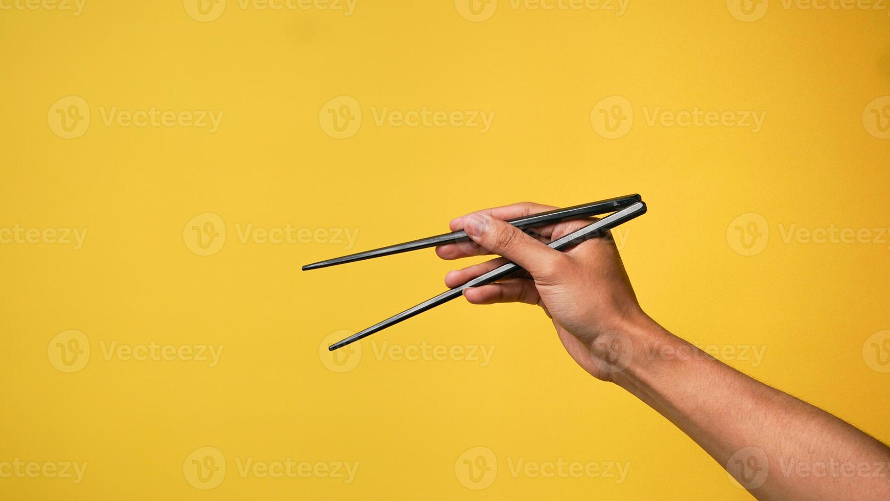 Man's hand pointing finger at camera on yellow background photo