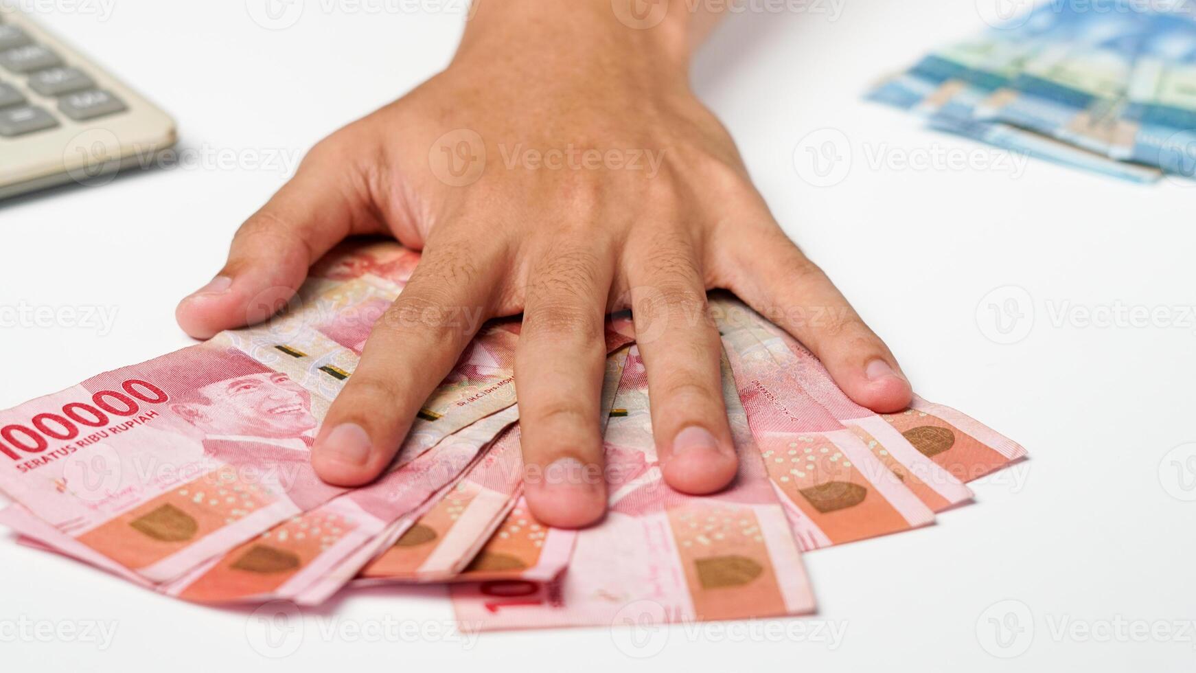 man's hand on a rupiah note. with a calculator on a white background photo