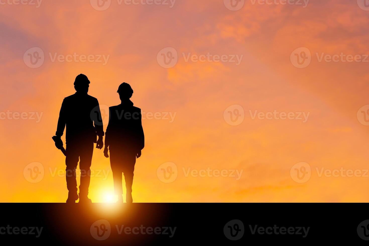 Silhouette of Engineer and foreman worker with blurred sunset in evening time background, construction concepts photo