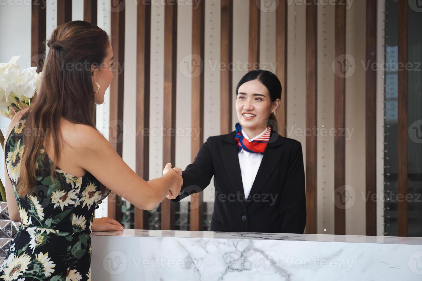 Receptionist and guest making handshake at hotel reception, Receptionist shaking hands with young female travelers at hotel counter photo