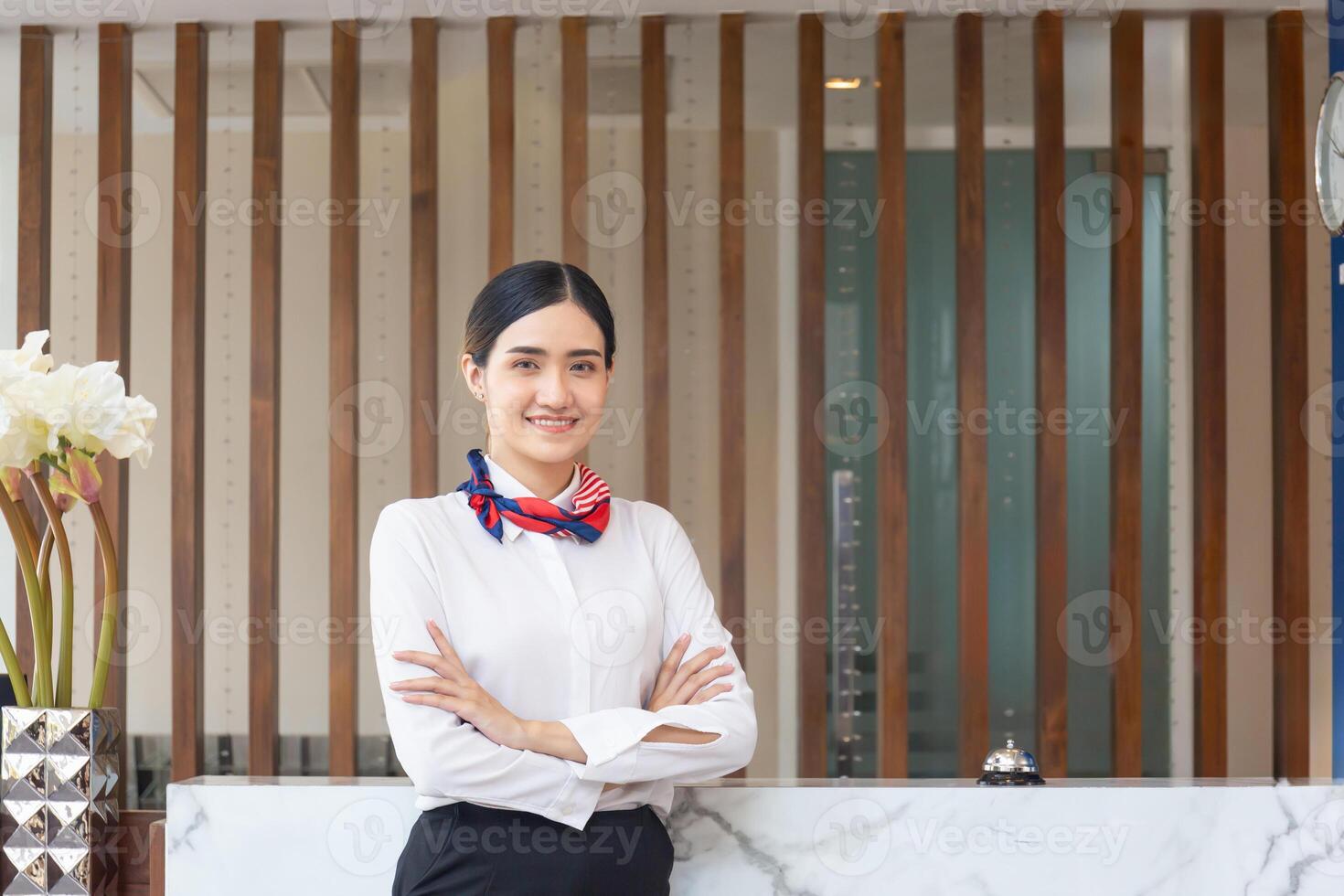 Young Asian woman receptionist at the hotel counter standing with arms crossed, Female receptionist working in the hostel photo