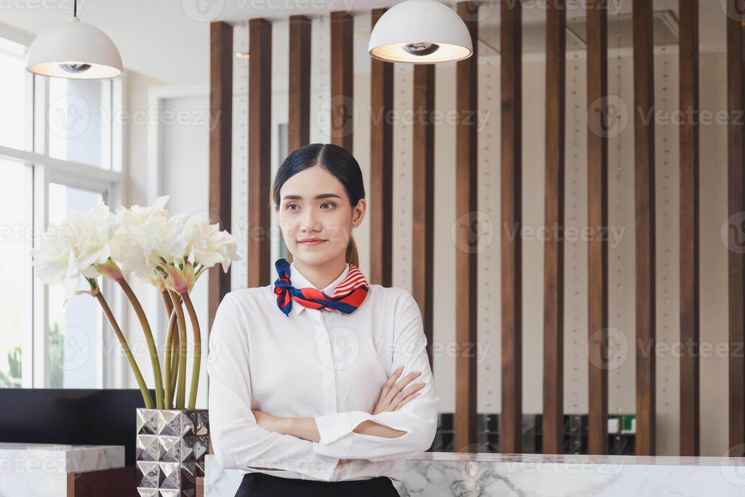 Young Asian woman receptionist at the hotel counter standing with arms crossed, Female receptionist working in the hotel photo