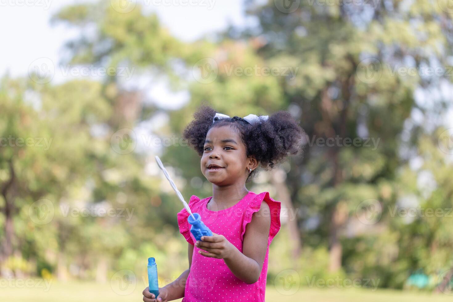 Happy kid girl playing with soap bubbles. Active child playing outdoors in the park photo