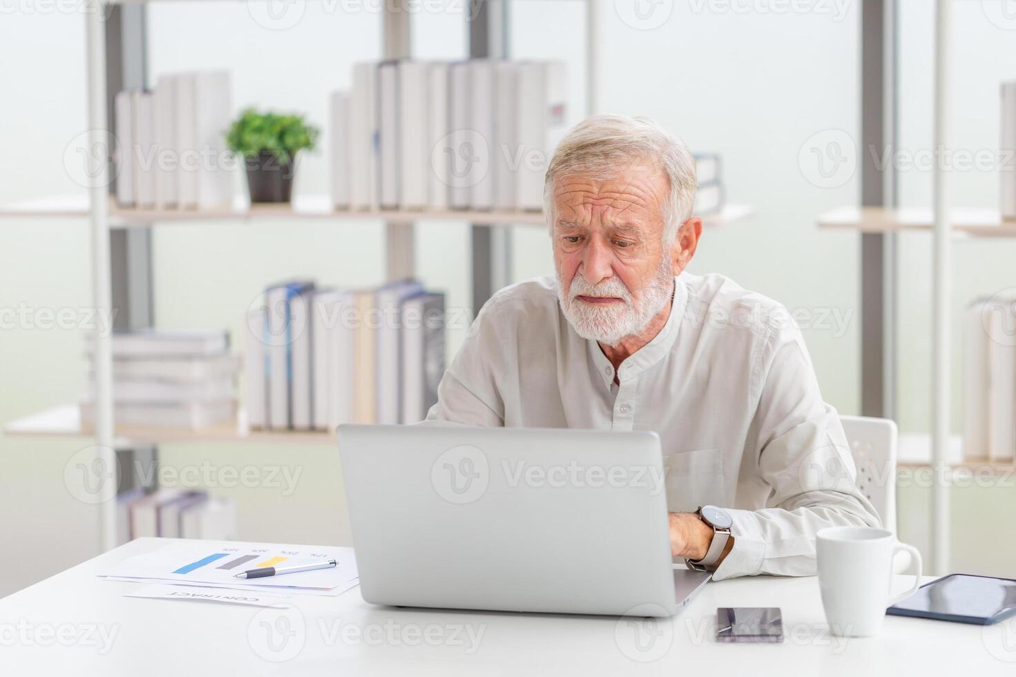 Senior man checking their bills, Mature man in the living room with laptop photo