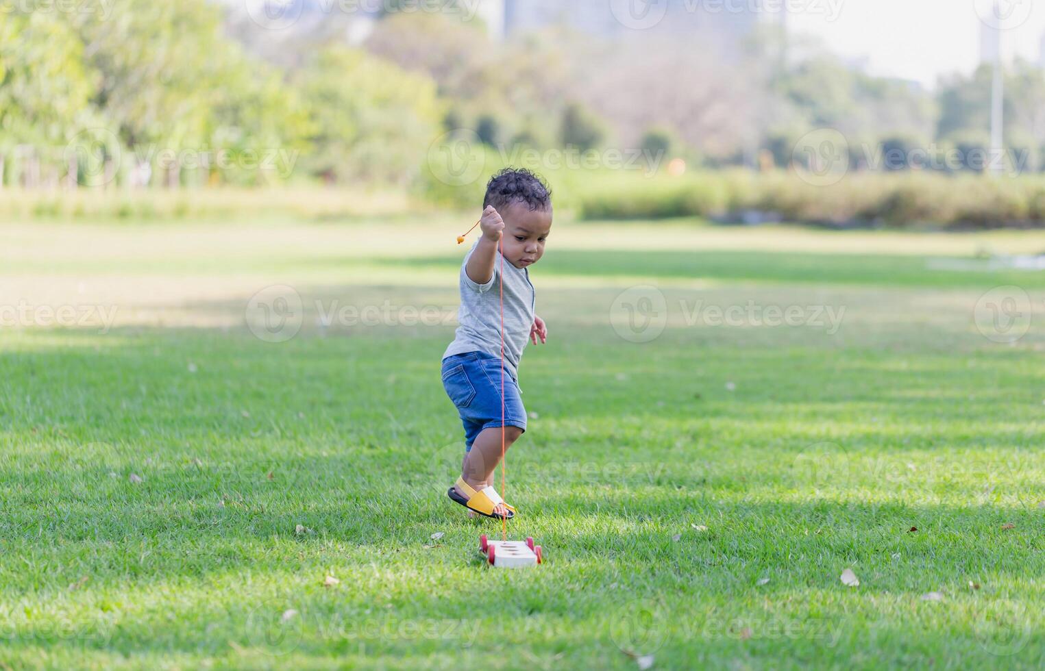 Cute little boy playing with toy in the garden, Child boy playing with little wooden toy cars outdoor photo