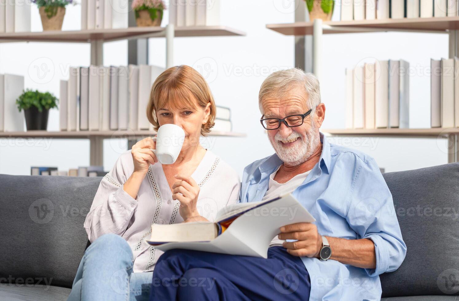 Senior couple in the living room, woman and man reading a book and enjoying coffee on the cozy sofa at home, Happy family concepts photo