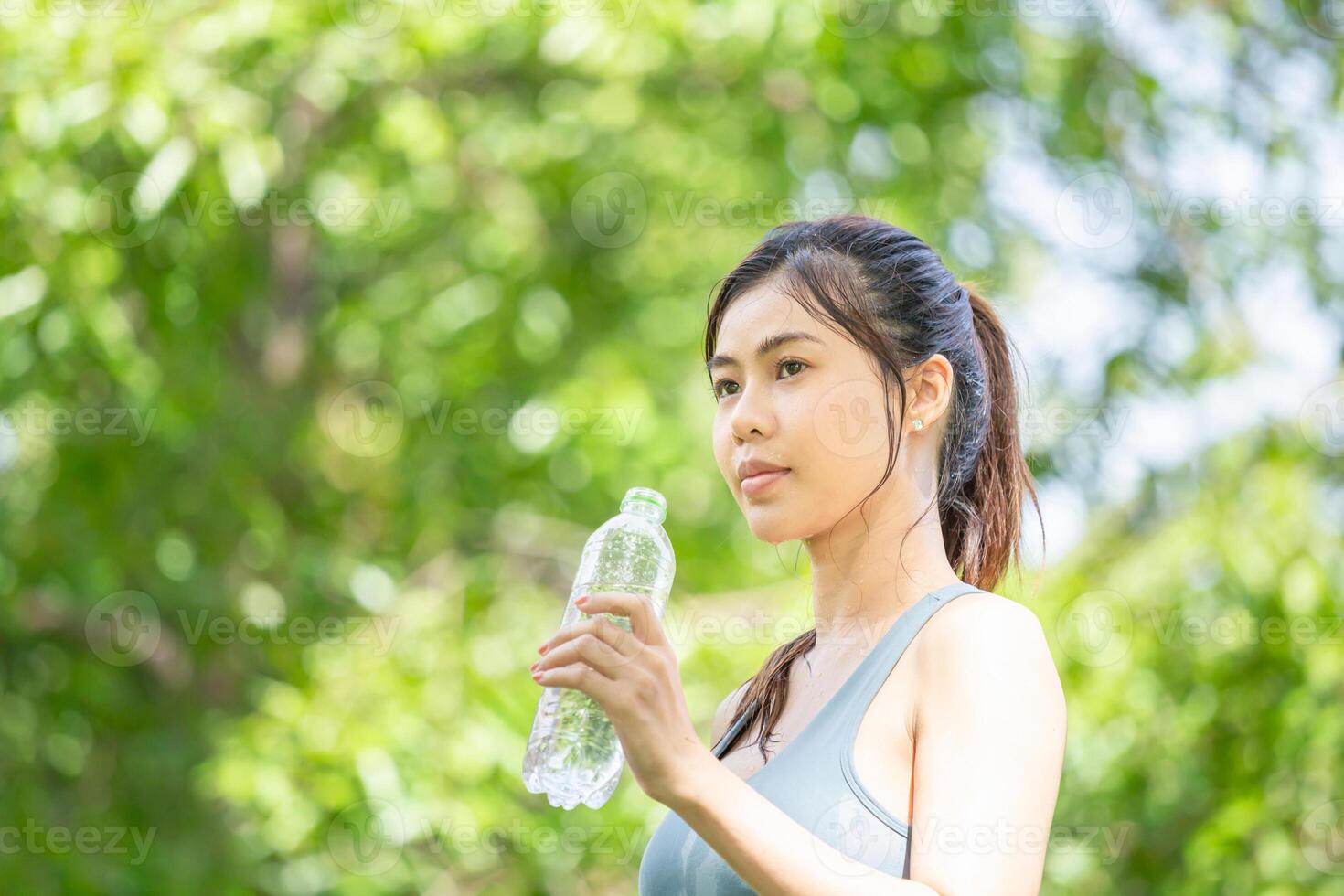 Athlete young beautiful woman with a plastic bottle at green park