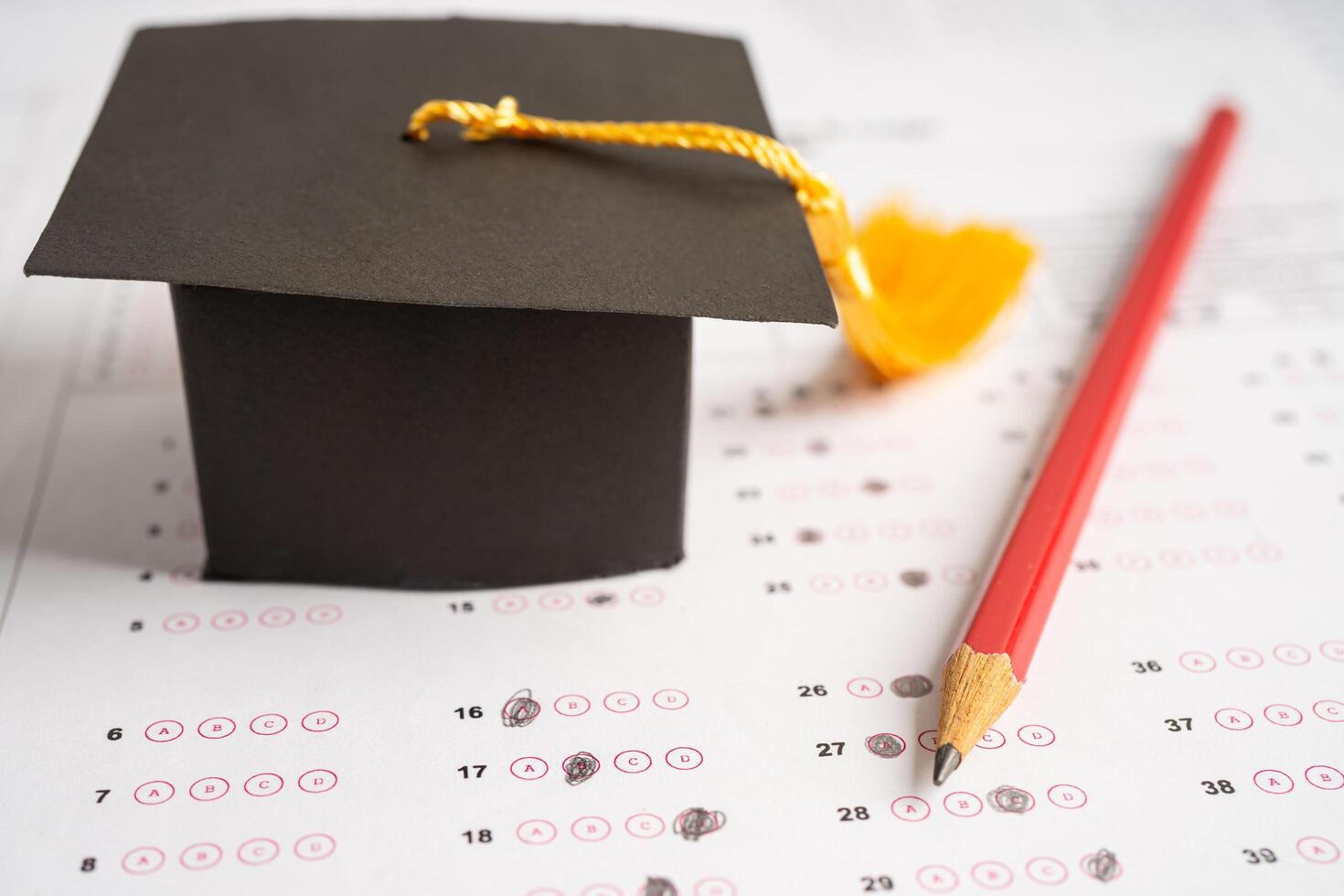 Graduation gap hat and pencil on answer sheet background, Education study testing learning teach concept. photo