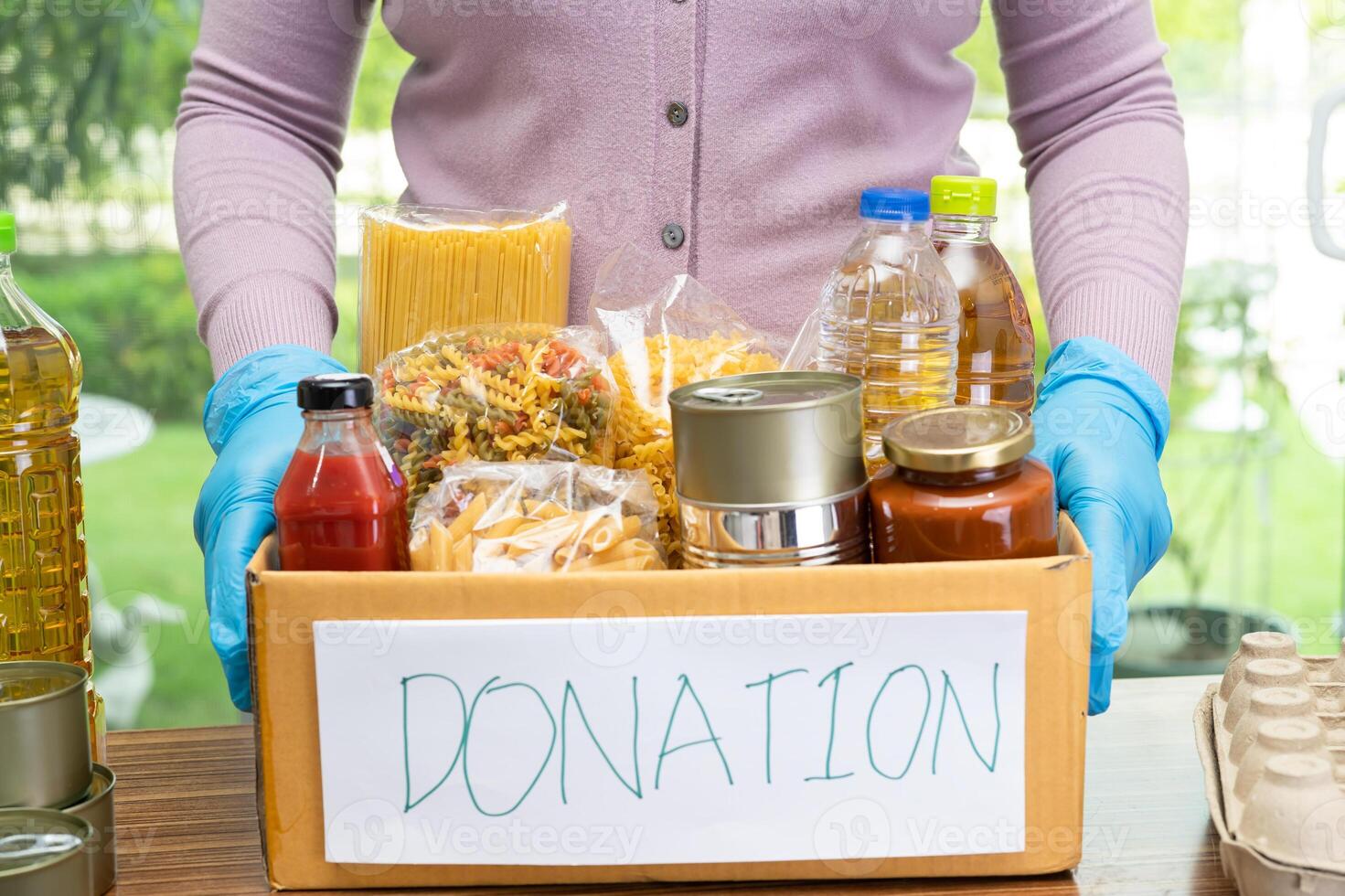 Volunteers putting various dry food in donation box for help people. photo