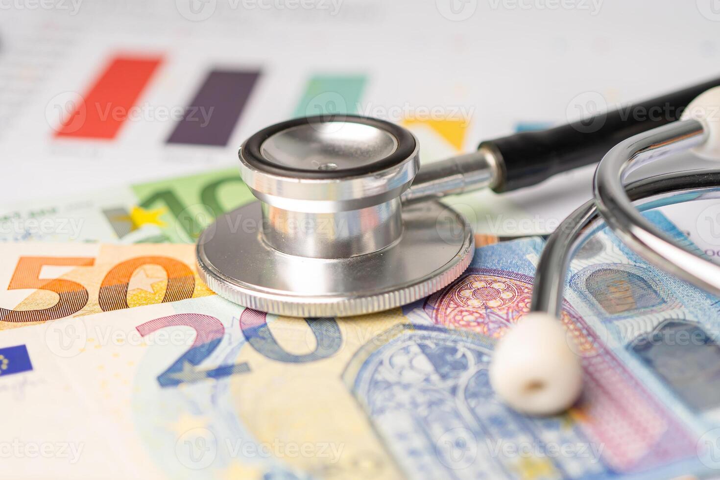 Stethoscope with Euro banknote on charts and graphs spreadsheet paper, Finance, Account, Statistics, Investment, Analytic research data economy and Business company. photo
