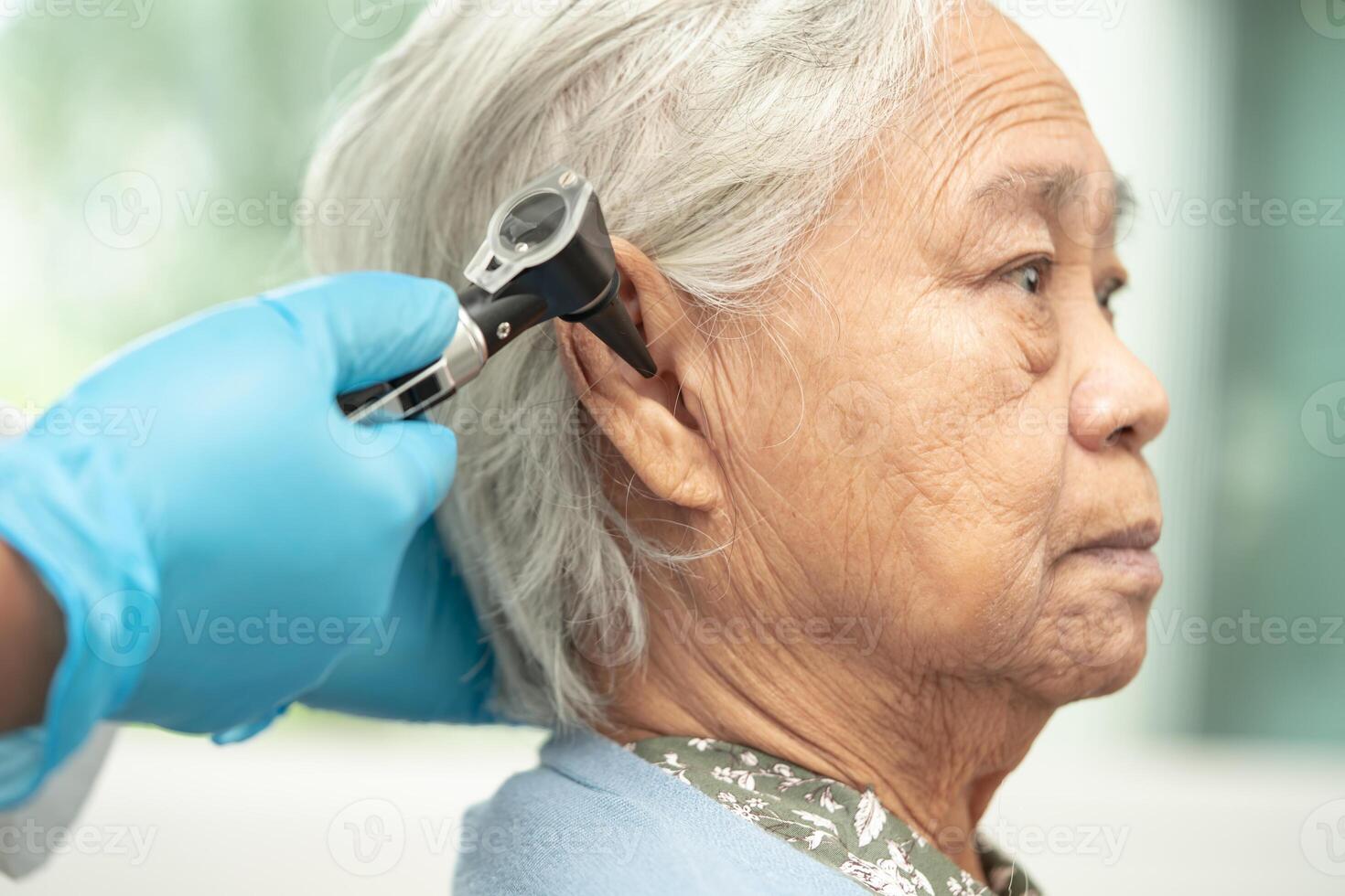 Audiologist or ENT doctor use otoscope checking ear of asian senior woman patient treating hearing loss problem. photo