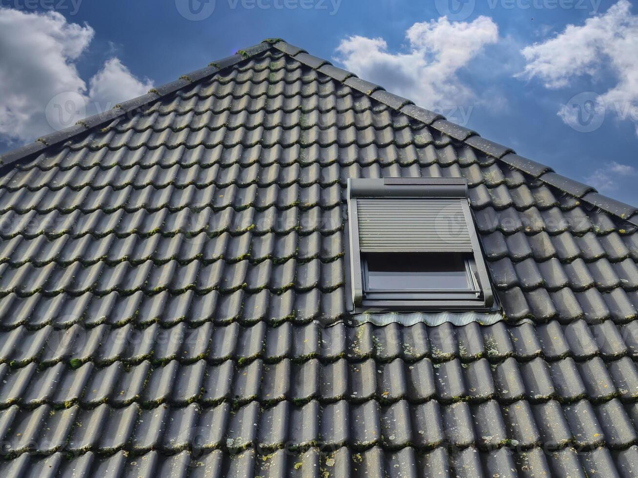 Open roof window in velux style with black roof tiles. photo