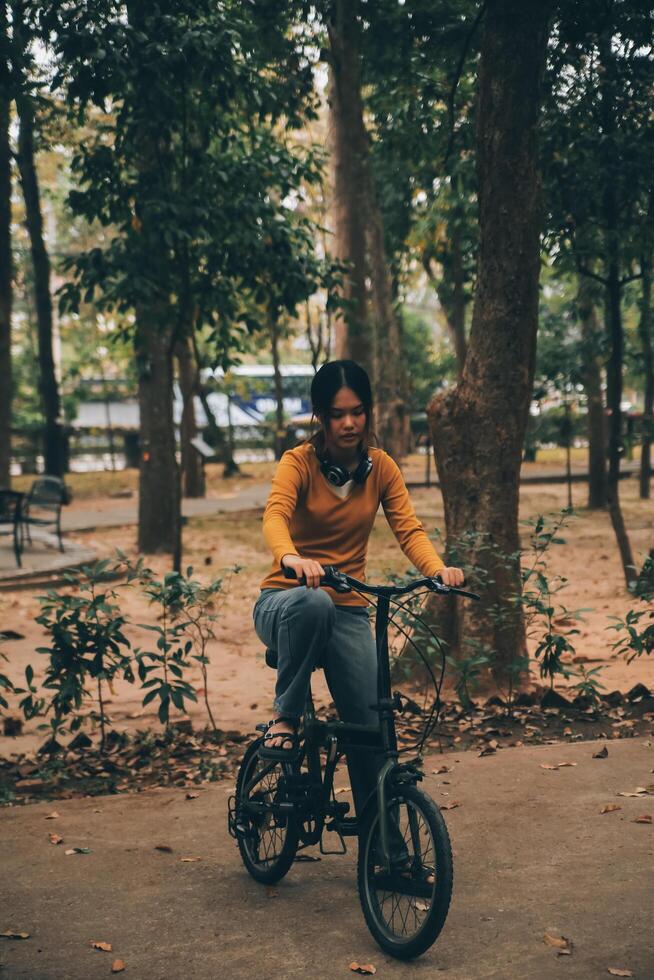 Happy young Asian woman while riding a bicycle in a city park. She smiled using the bicycle of transportation. Environmentally friendly concept. photo