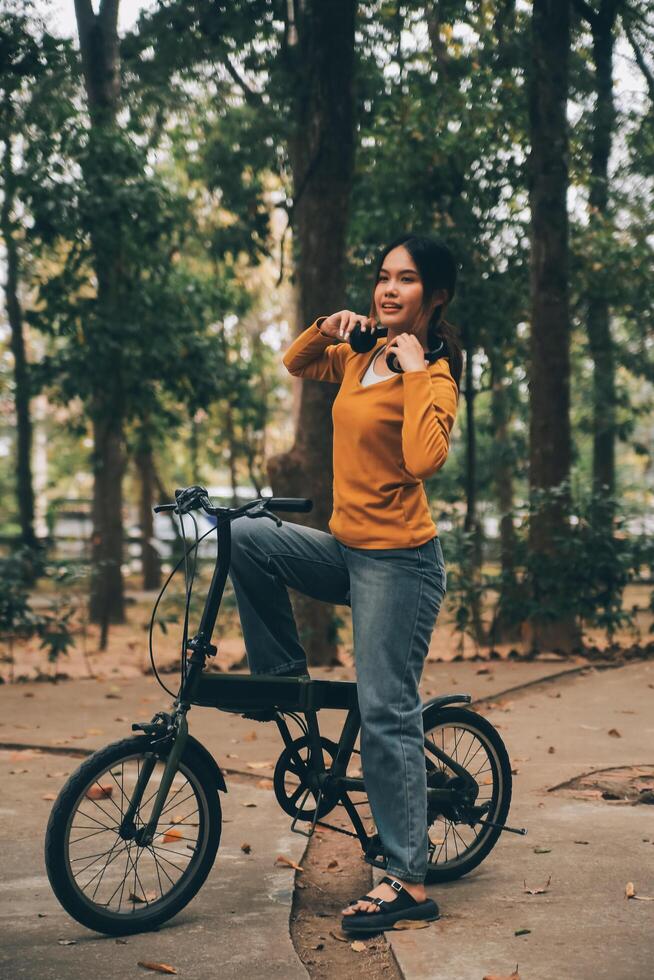 Happy young Asian woman while riding a bicycle in a city park. She smiled using the bicycle of transportation. Environmentally friendly concept. photo