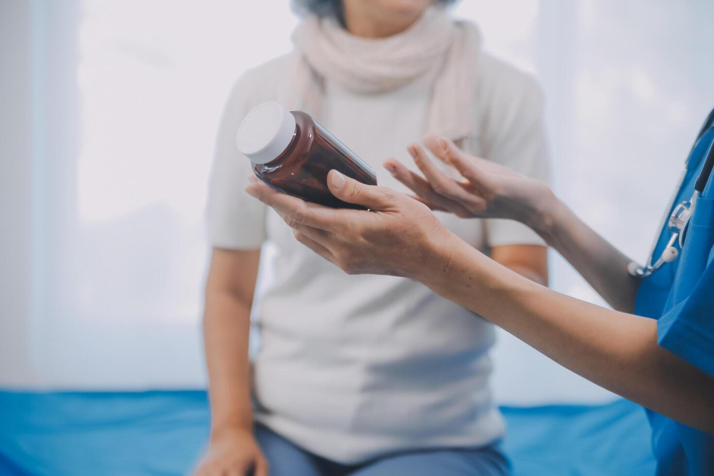 Asian woman nurse holding a medicine bottle and telling information to Asian senior woman before administering medication. Caregiver visit at home. Home health care and nursing home concept. photo