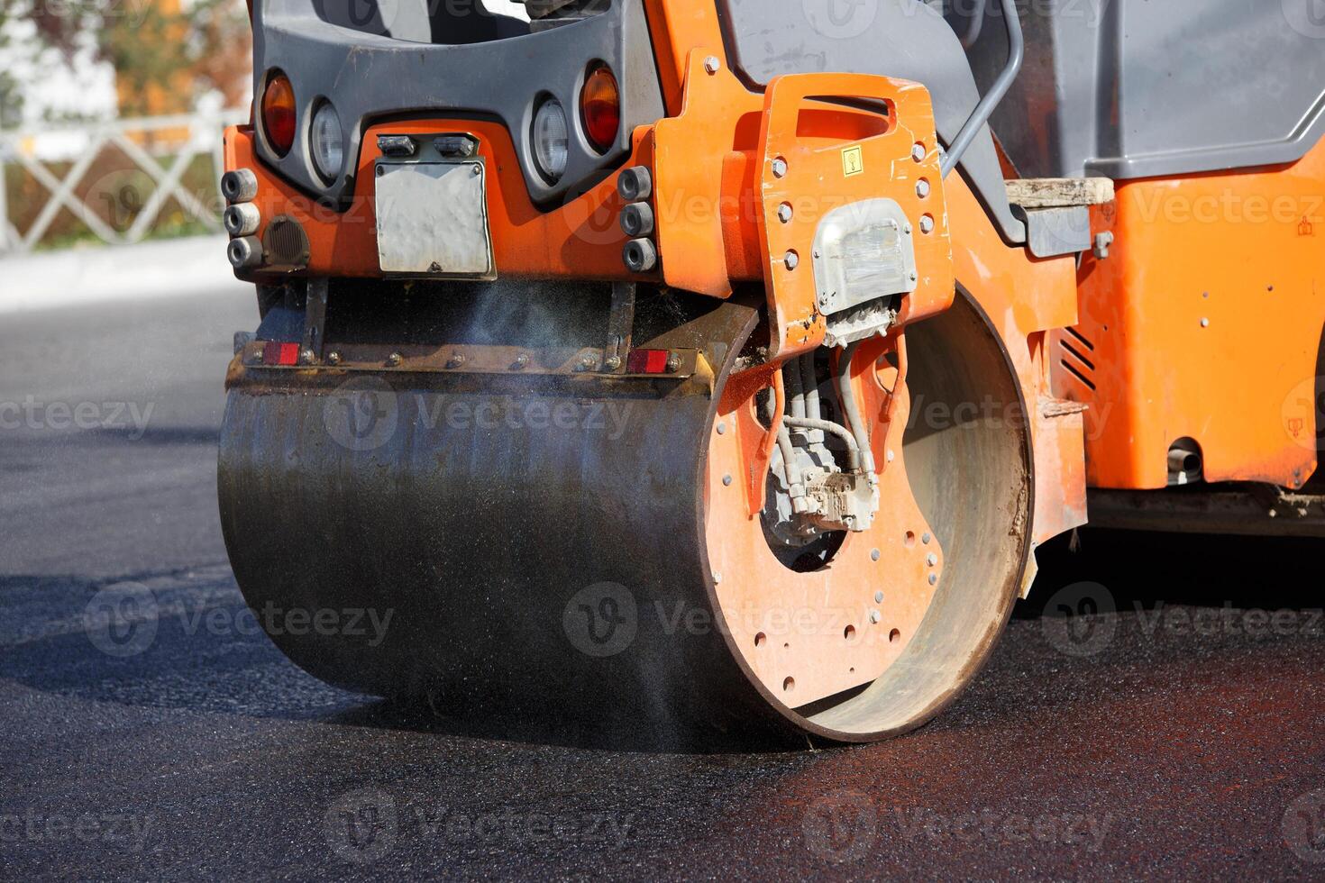 close-up view of steam roller working on new asphalt road at summer day light photo