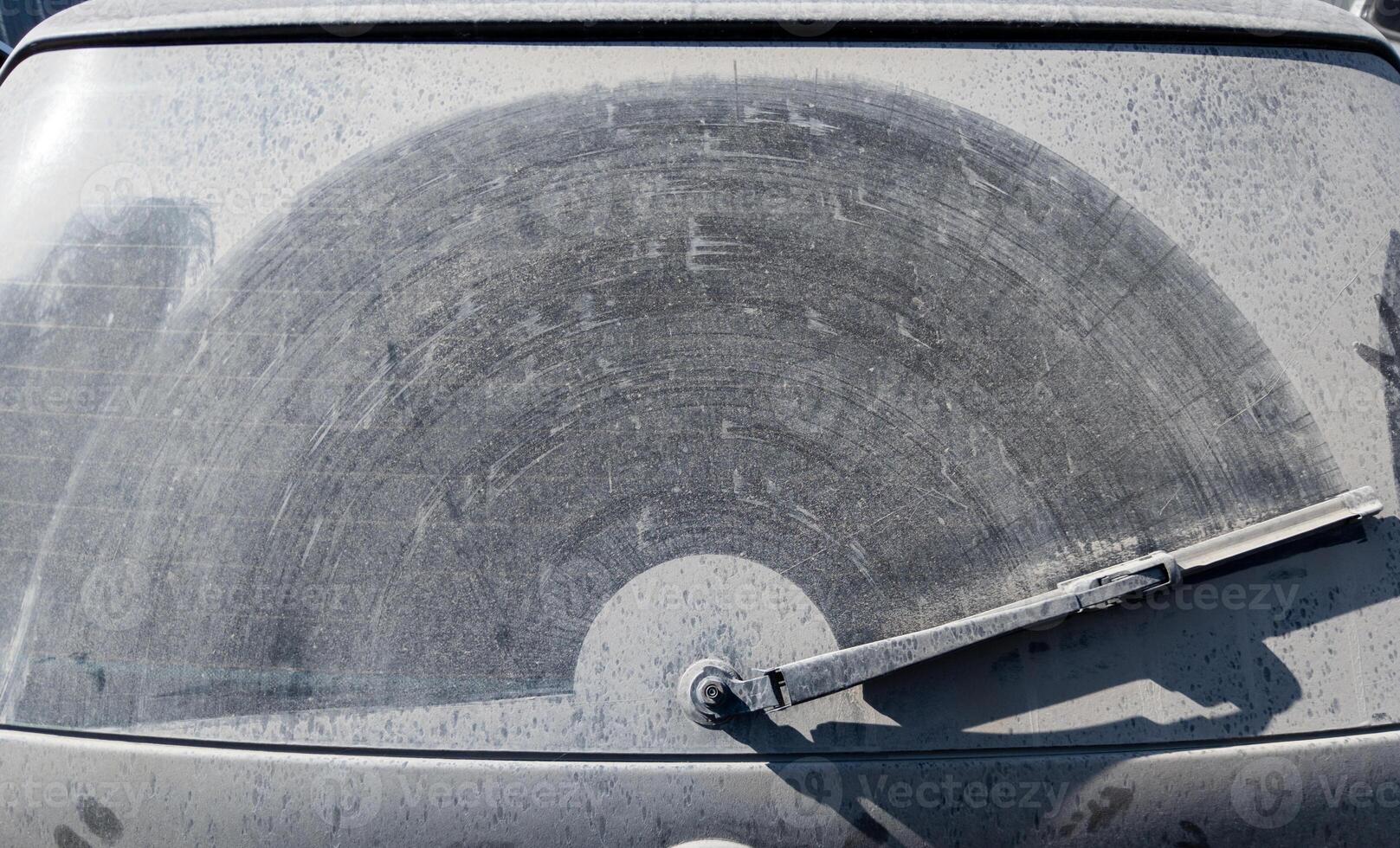 dusty rear window of the car with wiper trace on layer of dirt photo