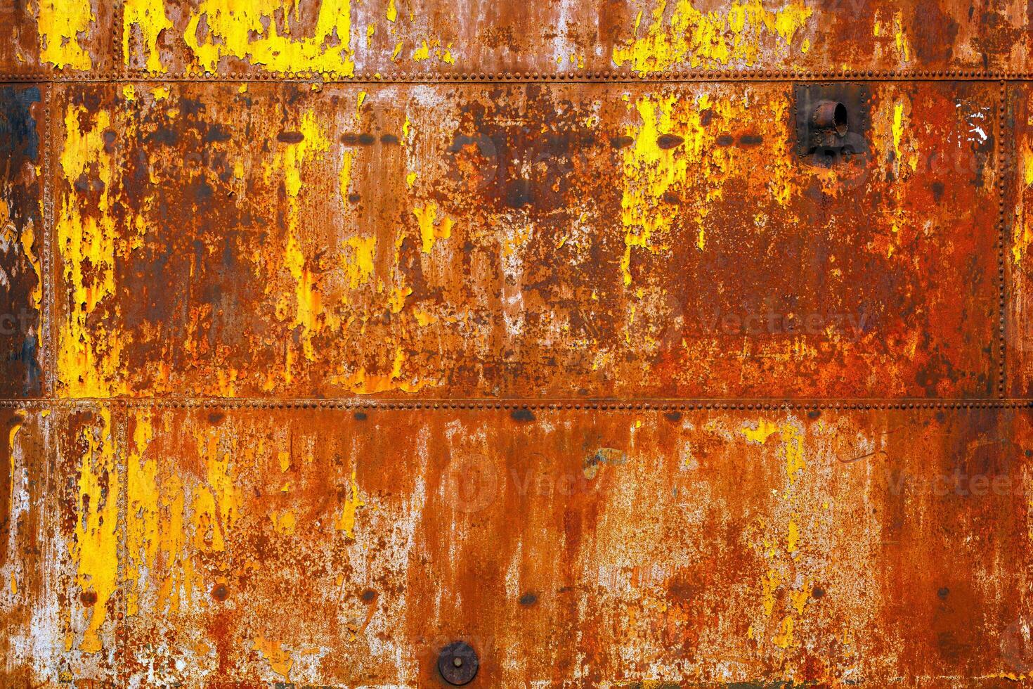 beautifully rusted rivetted sheet metal with leftovers of yellow paint texture and full-frame background photo