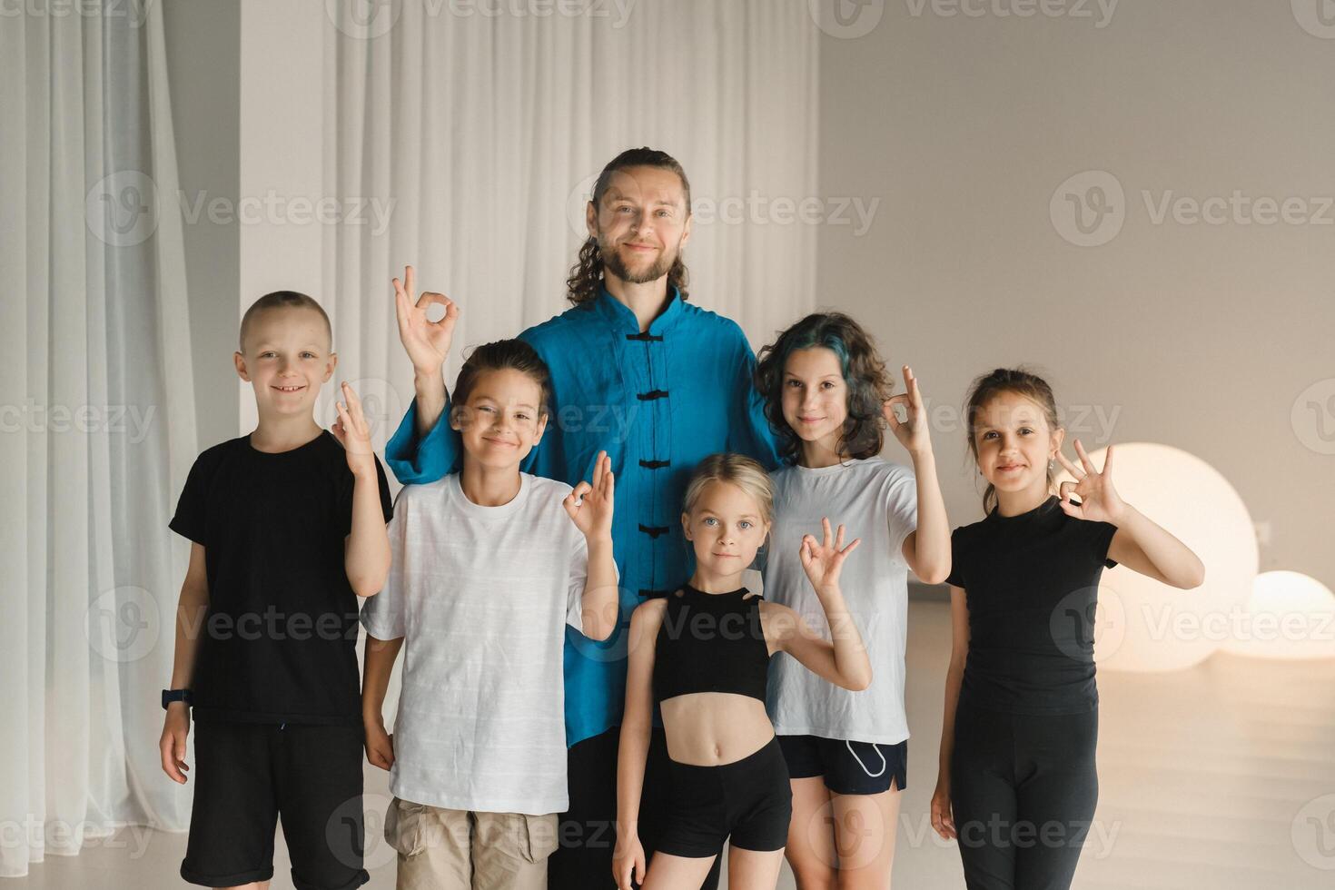 A joint portrait of a yoga coach and children standing in a fitness room photo