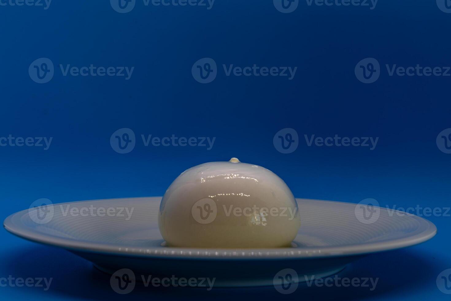 Burrata cheese Sitting on Plate on Blue Background photo