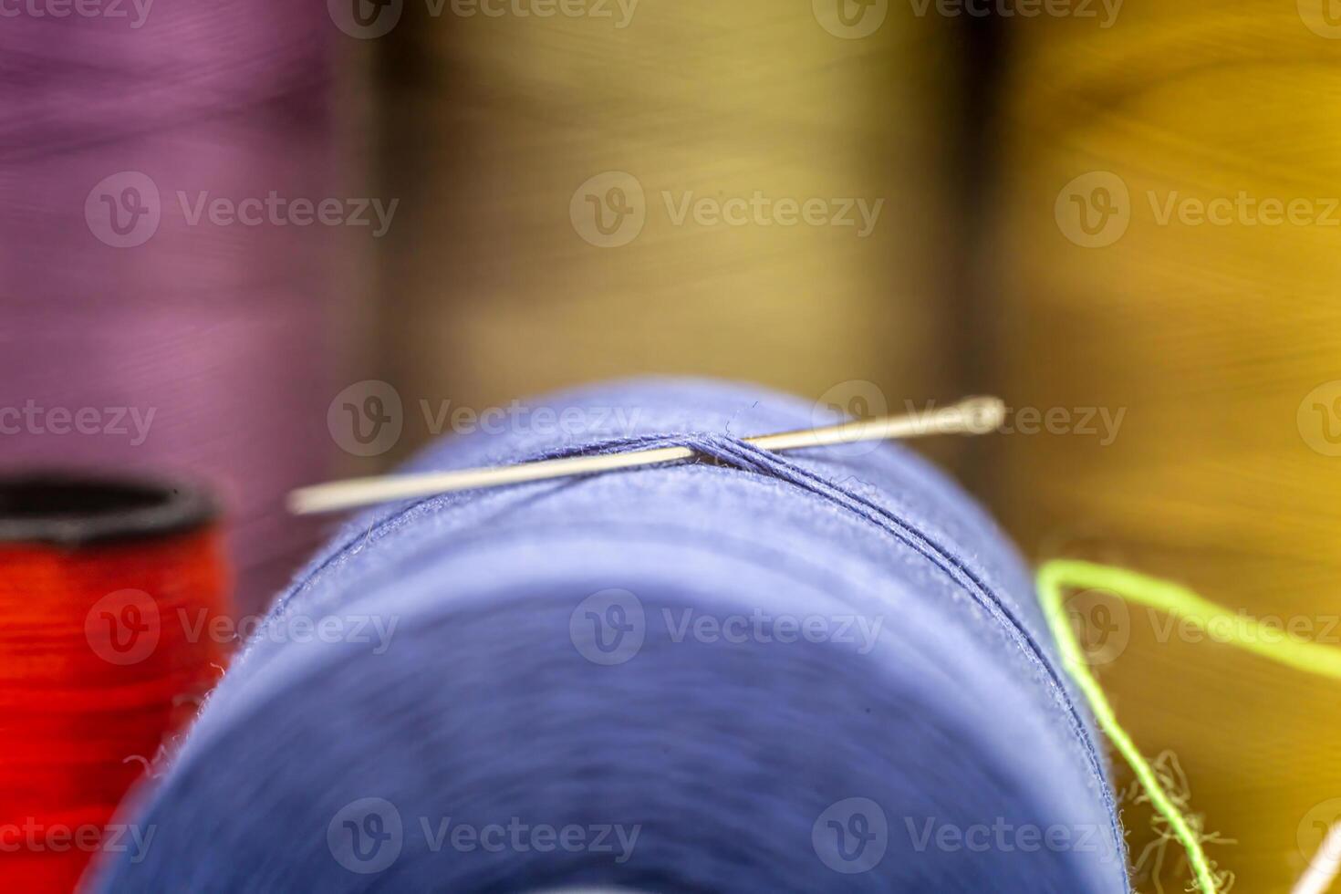 Closeup of a needle in a thread with other colorful needles in the blurry background photo