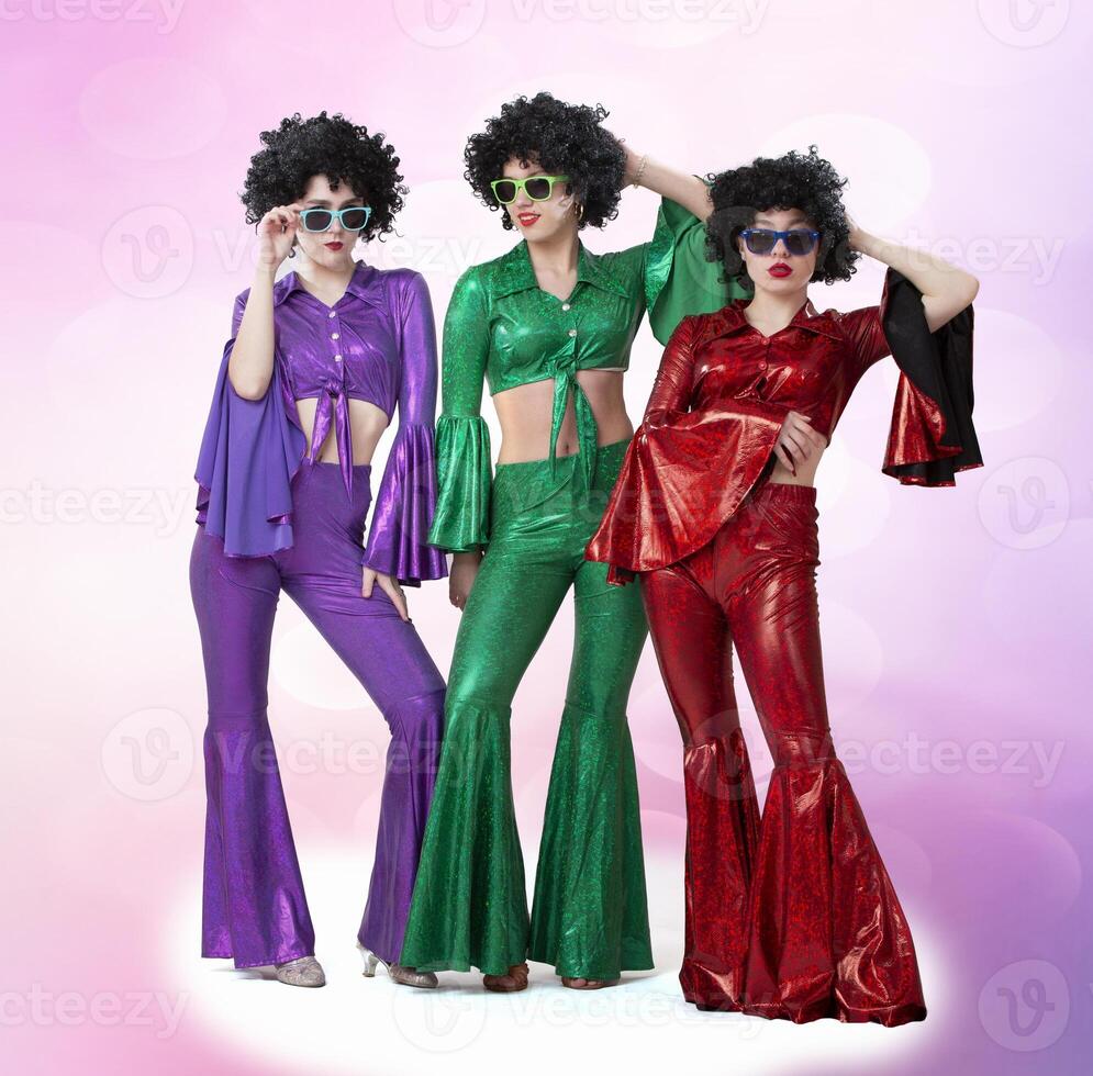 A group of girls in disco style and African wigs in colorful costumes on a pink background. Singers and dancers of the eighties and seventies. photo