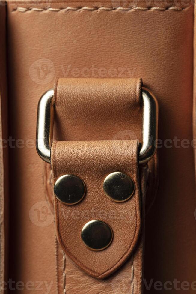 Part of a bag made of brown genuine leather with a metal fastening for the handle. photo