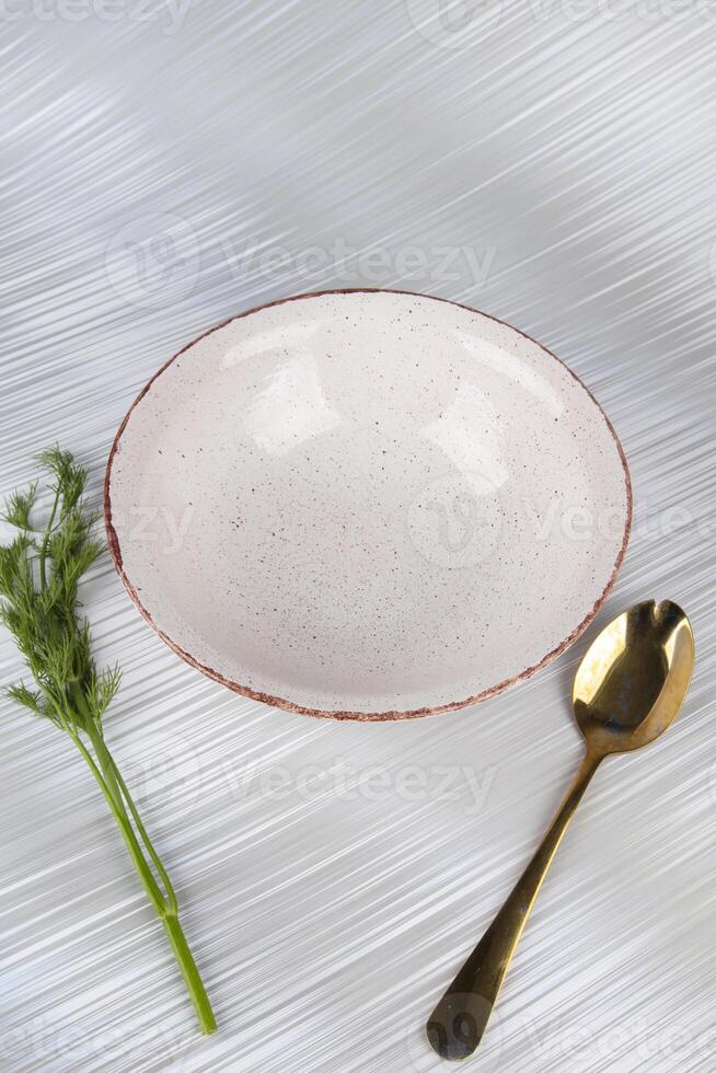 White empty deep clay plate with a spoon on a white background. photo