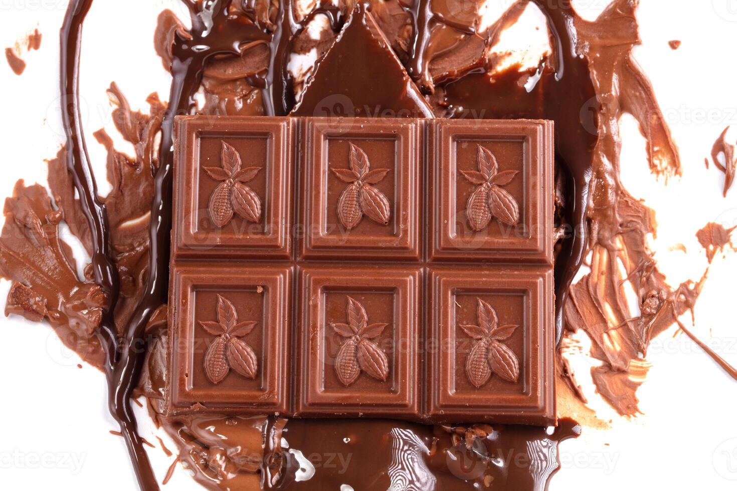 Sweet melted chocolate background with chocolate squares on which cocoa beans are drawn. Mass of chocolate. photo