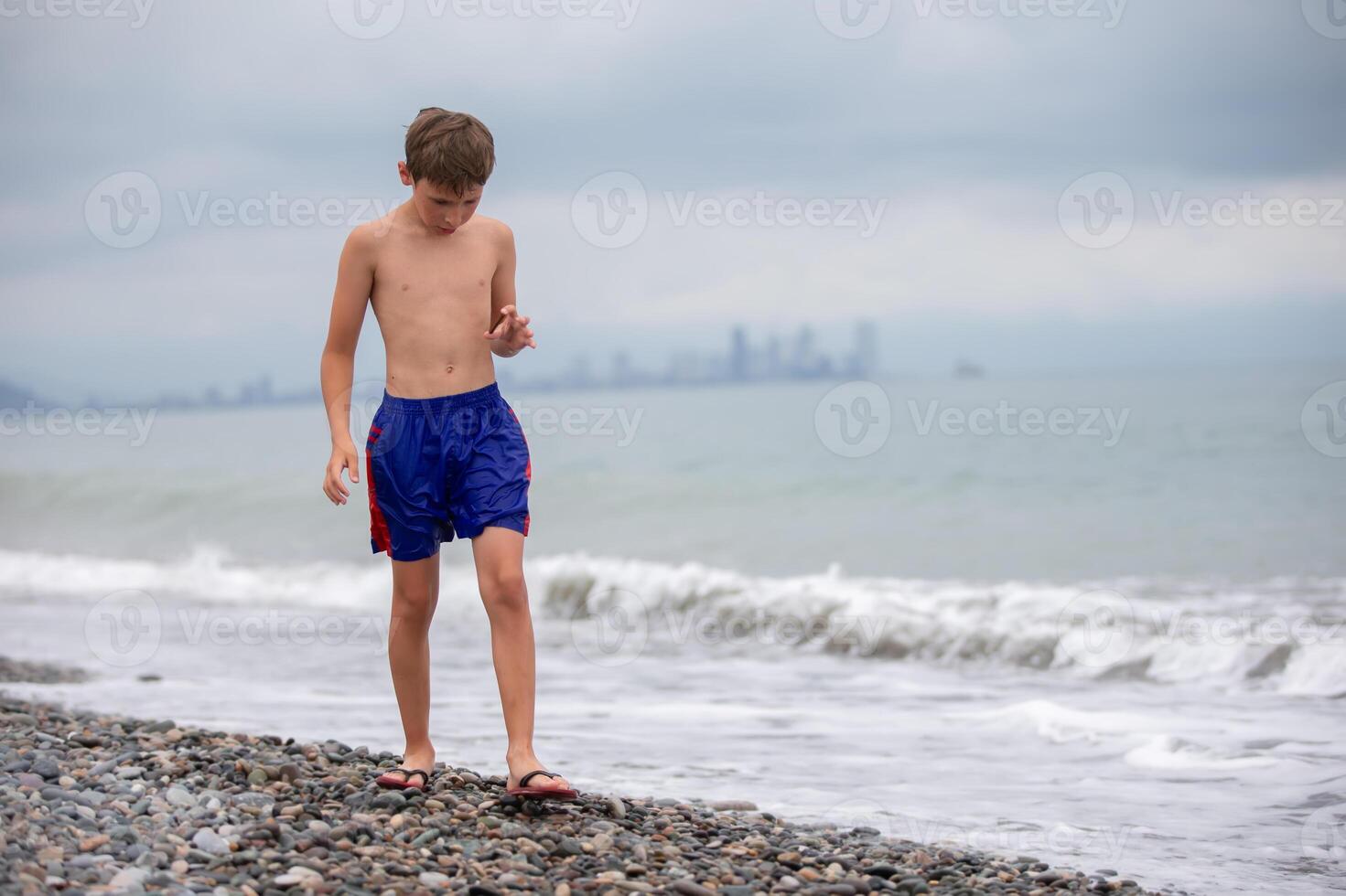 The boy walks along the rocky shore of the sea. photo