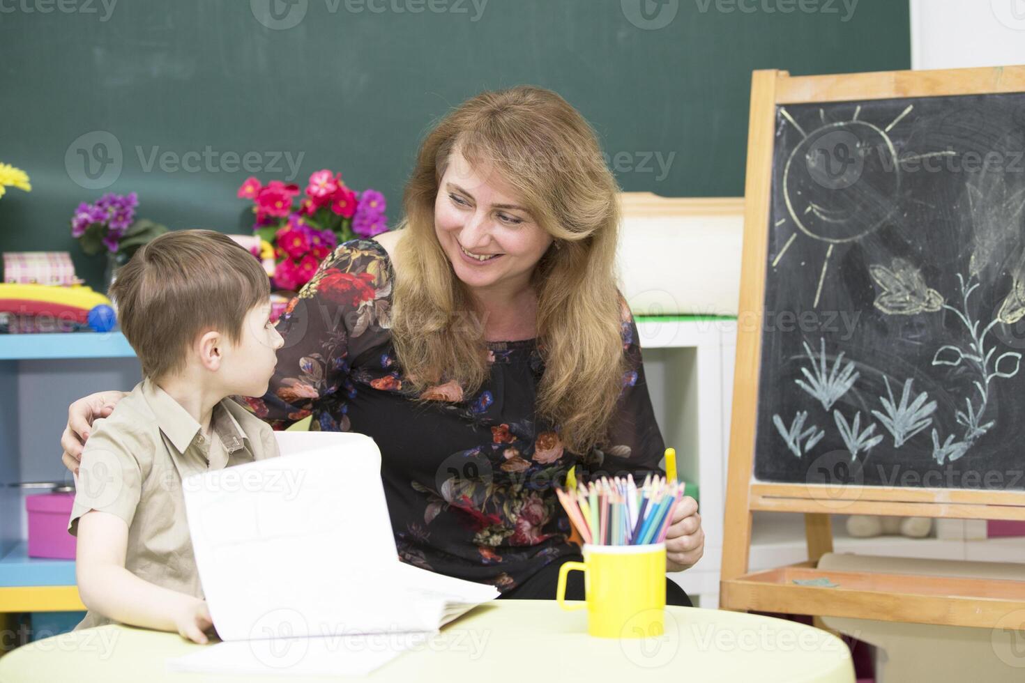 profesor con un preescolar mujer con un júnior estudiante en un brillante para niños habitación foto