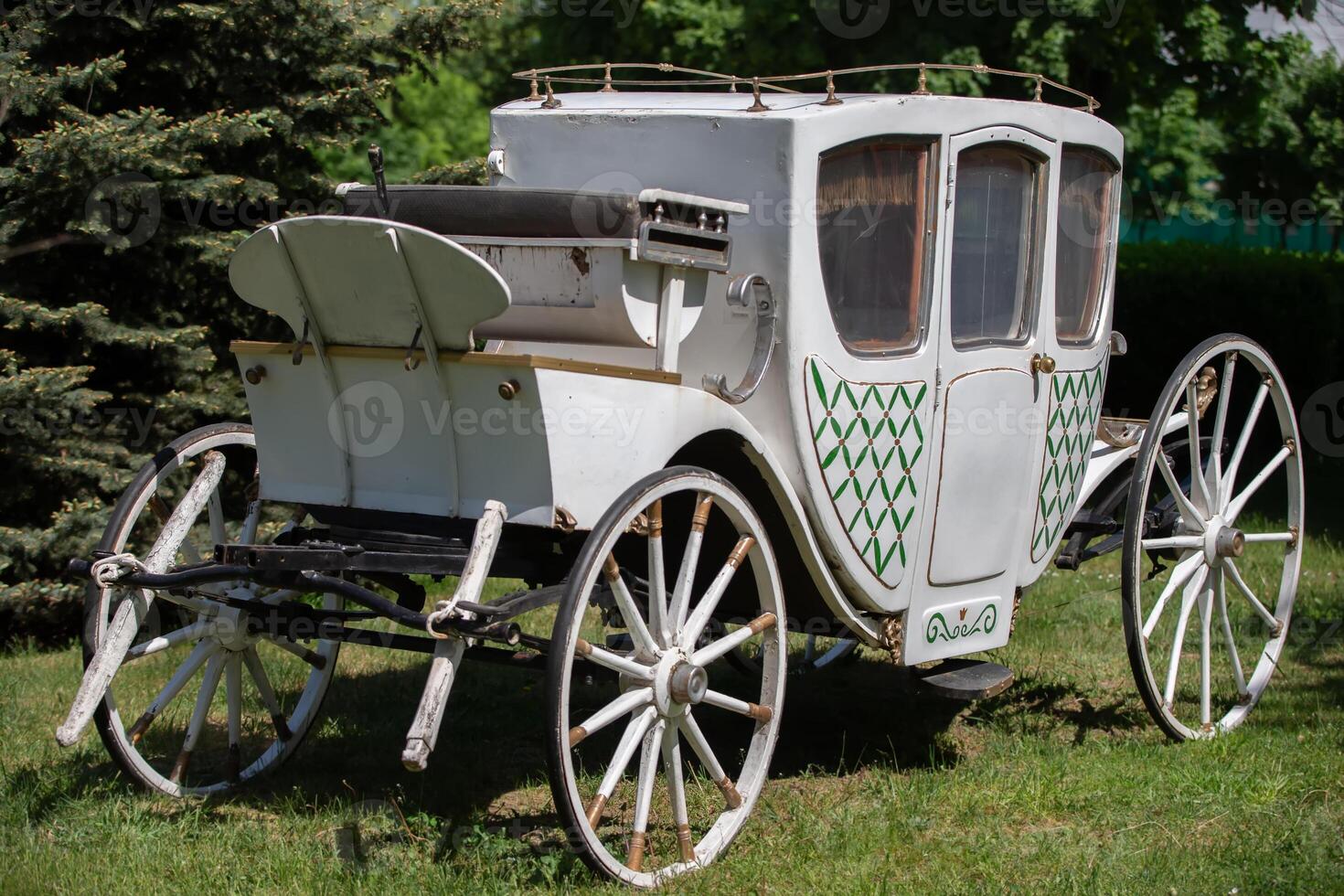 An antique white carriage from the nineteenth century on a green lawn. The prototype of a modern car. photo