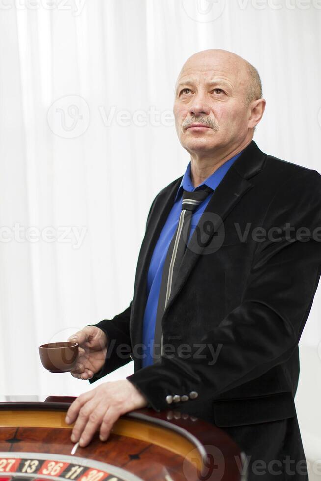 Elegant elderly man in a casino with a cup of coffee photo