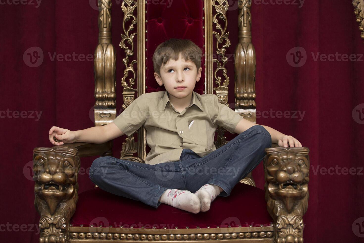 Child dreams in a royal red chair photo