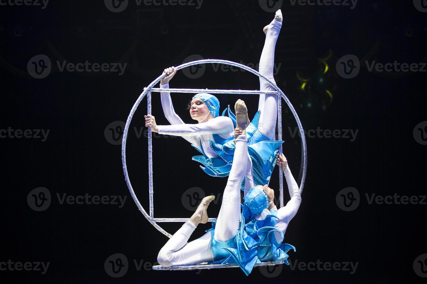 Two acrobat girls show a circus number on a dark background. Acrobatic performance. photo
