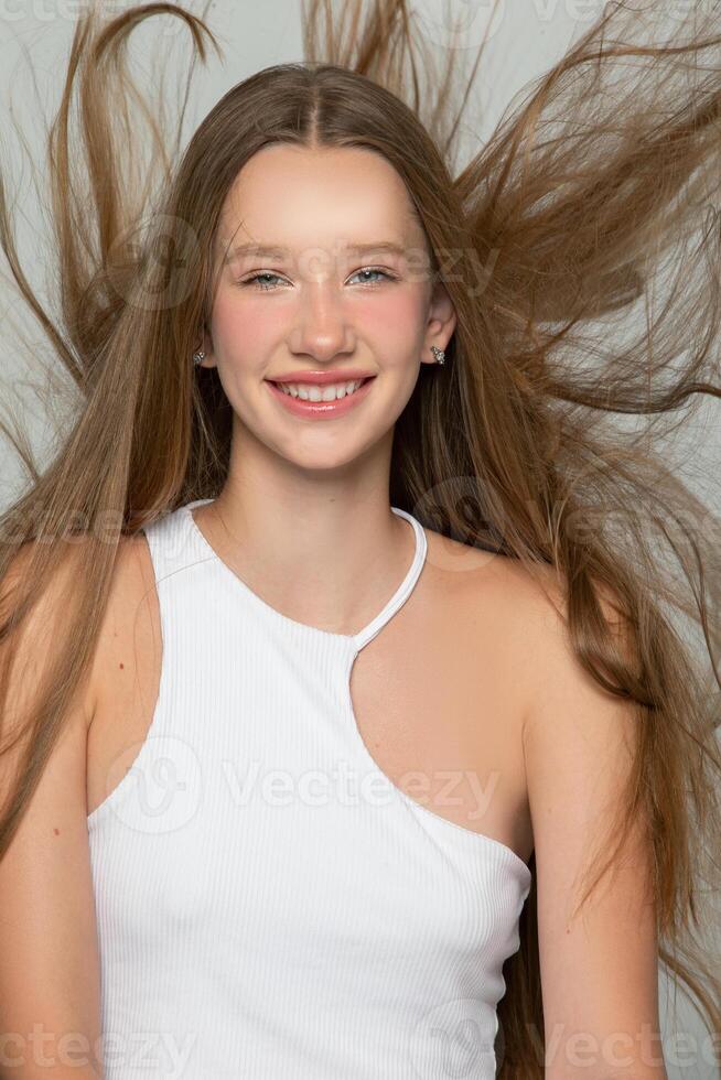 Happy blonde with long flowing hair. Portrait of a girl with a smile. photo