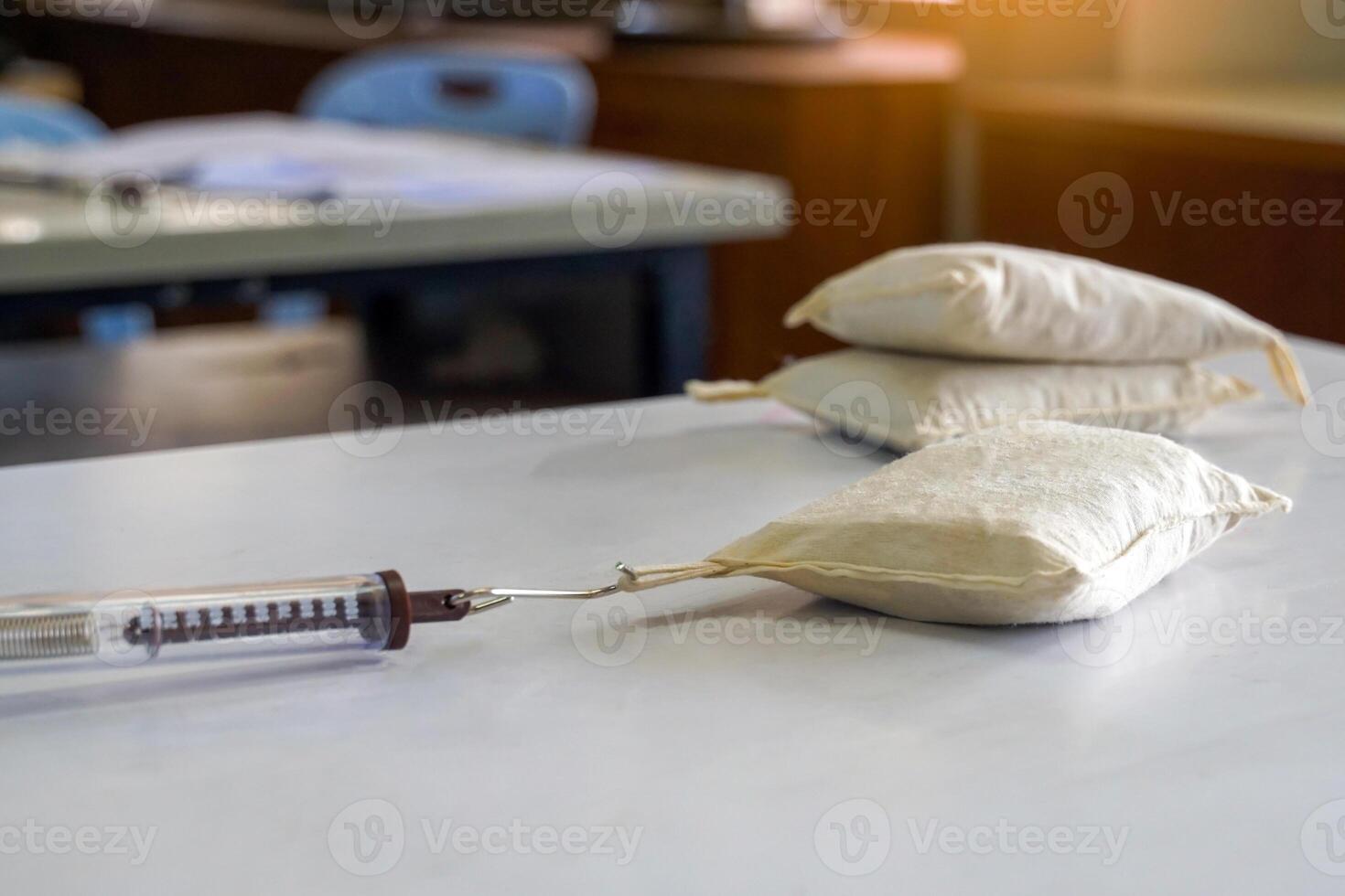Asian students perform a physics experiment using a cylindrical Spring Balance pulling a sandbag placed on a workbench to measure the force pulling the sandbag into motion. photo