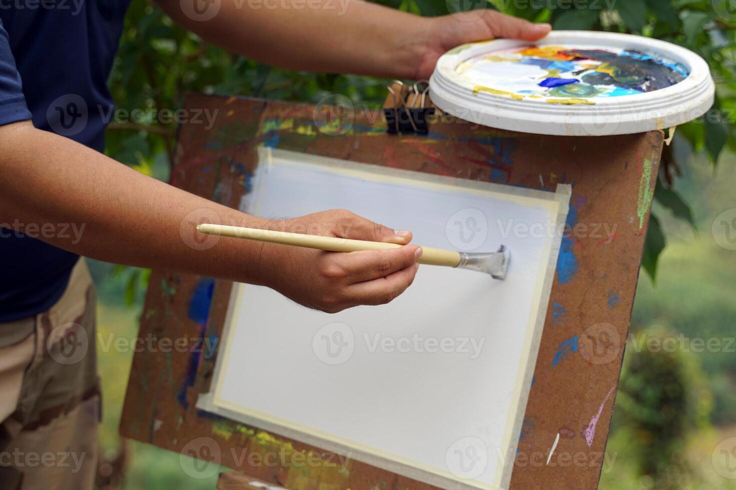 An art teacher teaches landscape painting with watercolors to children attending art camp. Soft and selective focus. photo