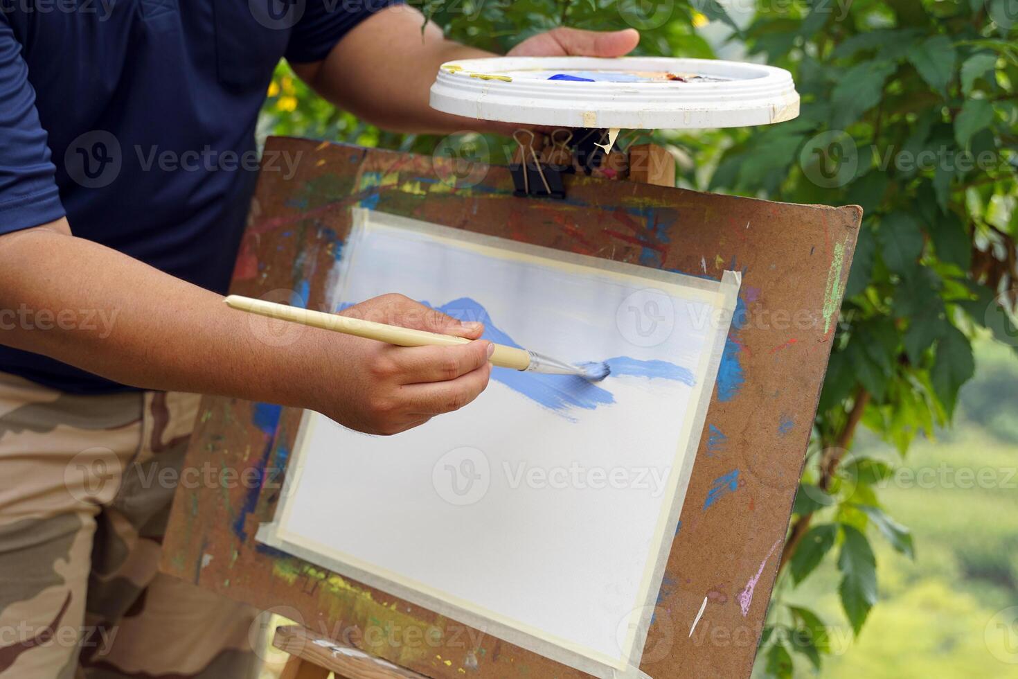 An art teacher teaches landscape painting with watercolors to children attending art camp. Soft and selective focus. photo