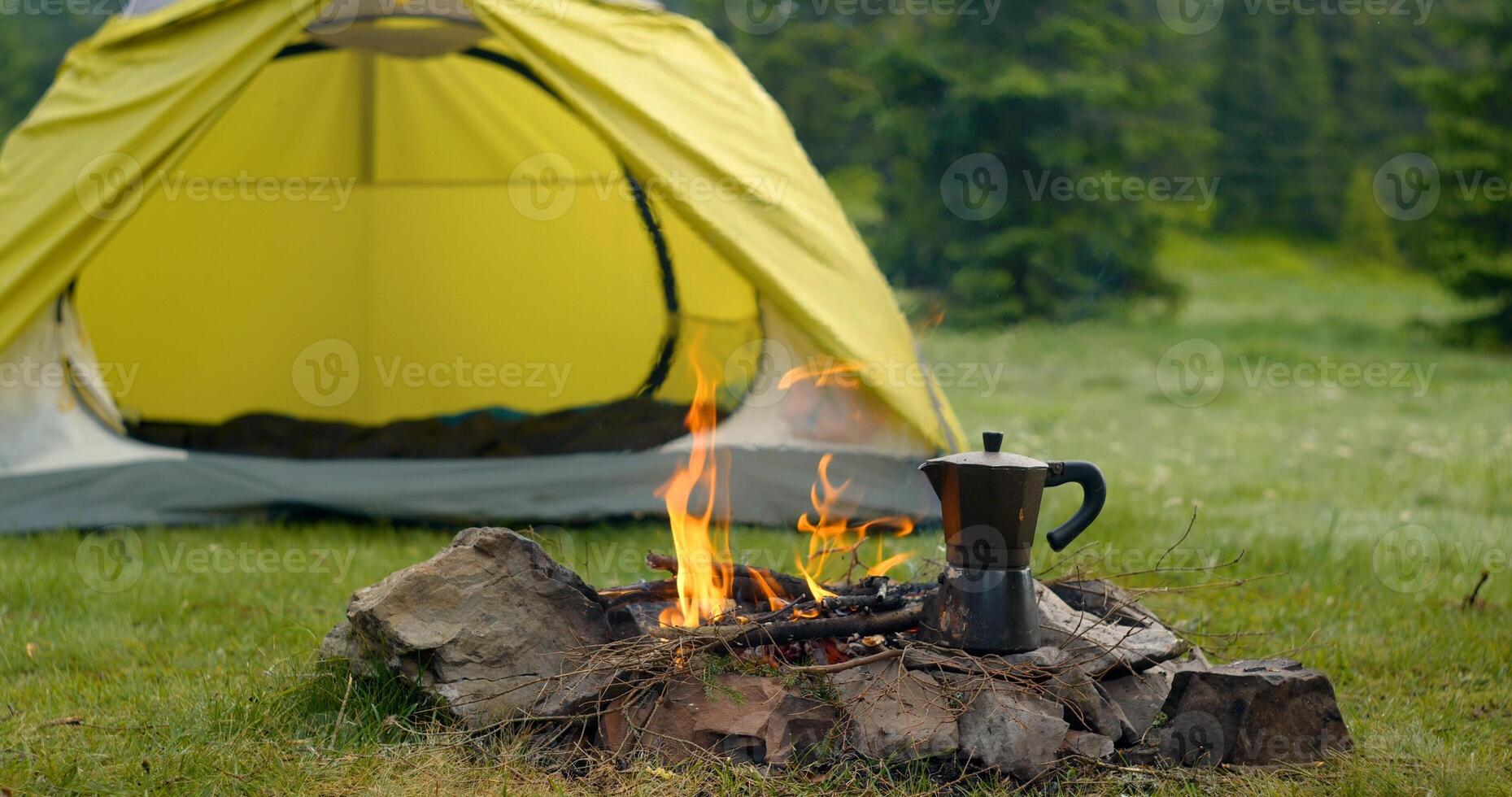 Tent and bonfire on the forest lawn in the mountains. Travel concept photo