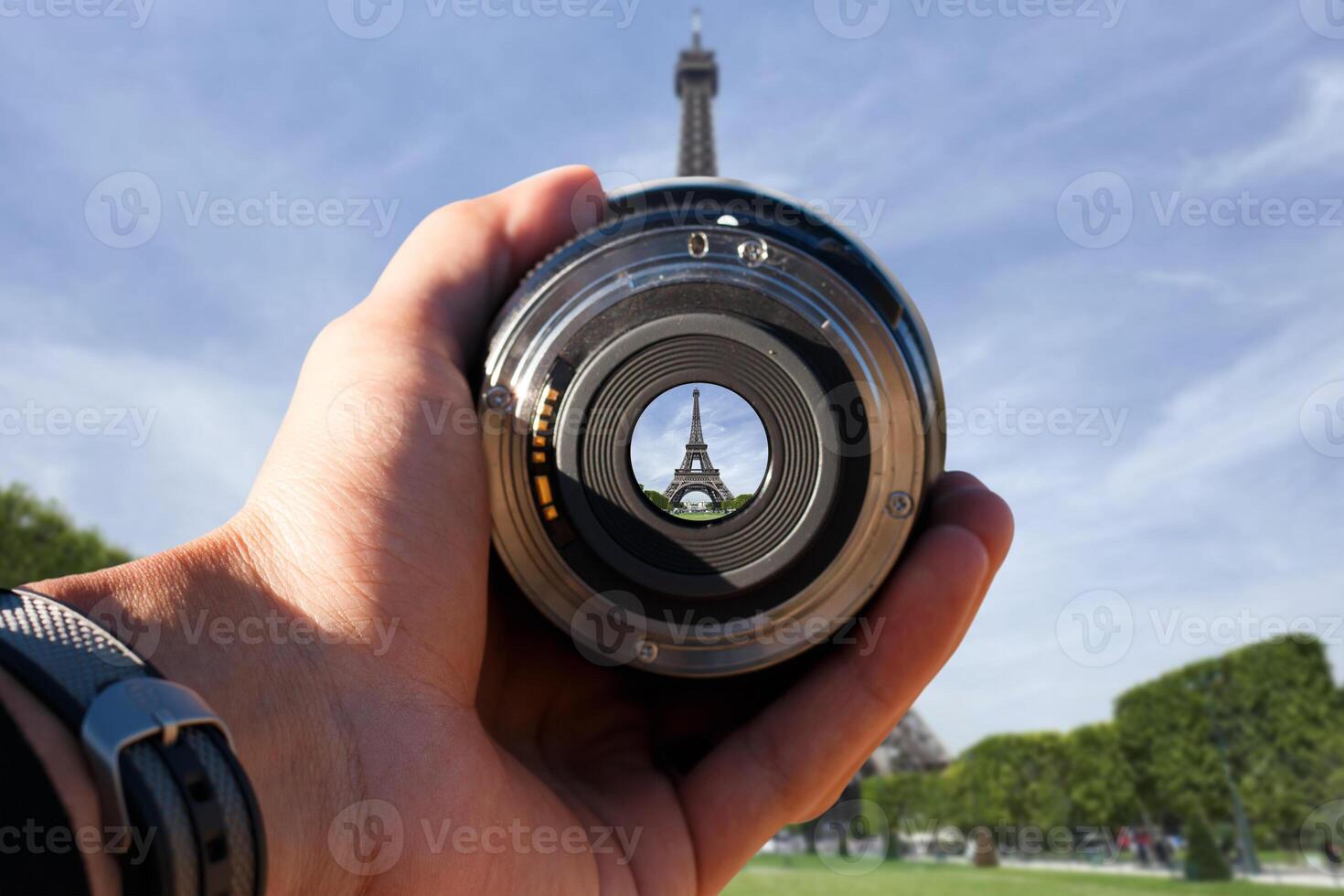 selective focus shot person holding camera lens on effil tower tourist taking a picture with camera lens on eiffel tower photo