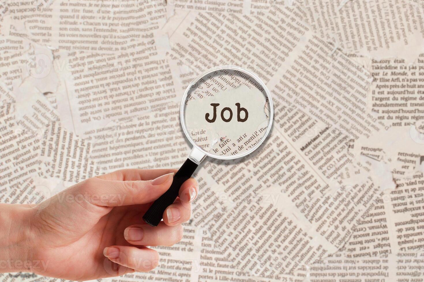 Hand with Look close with Magnifying glass on Job background newspaper photo