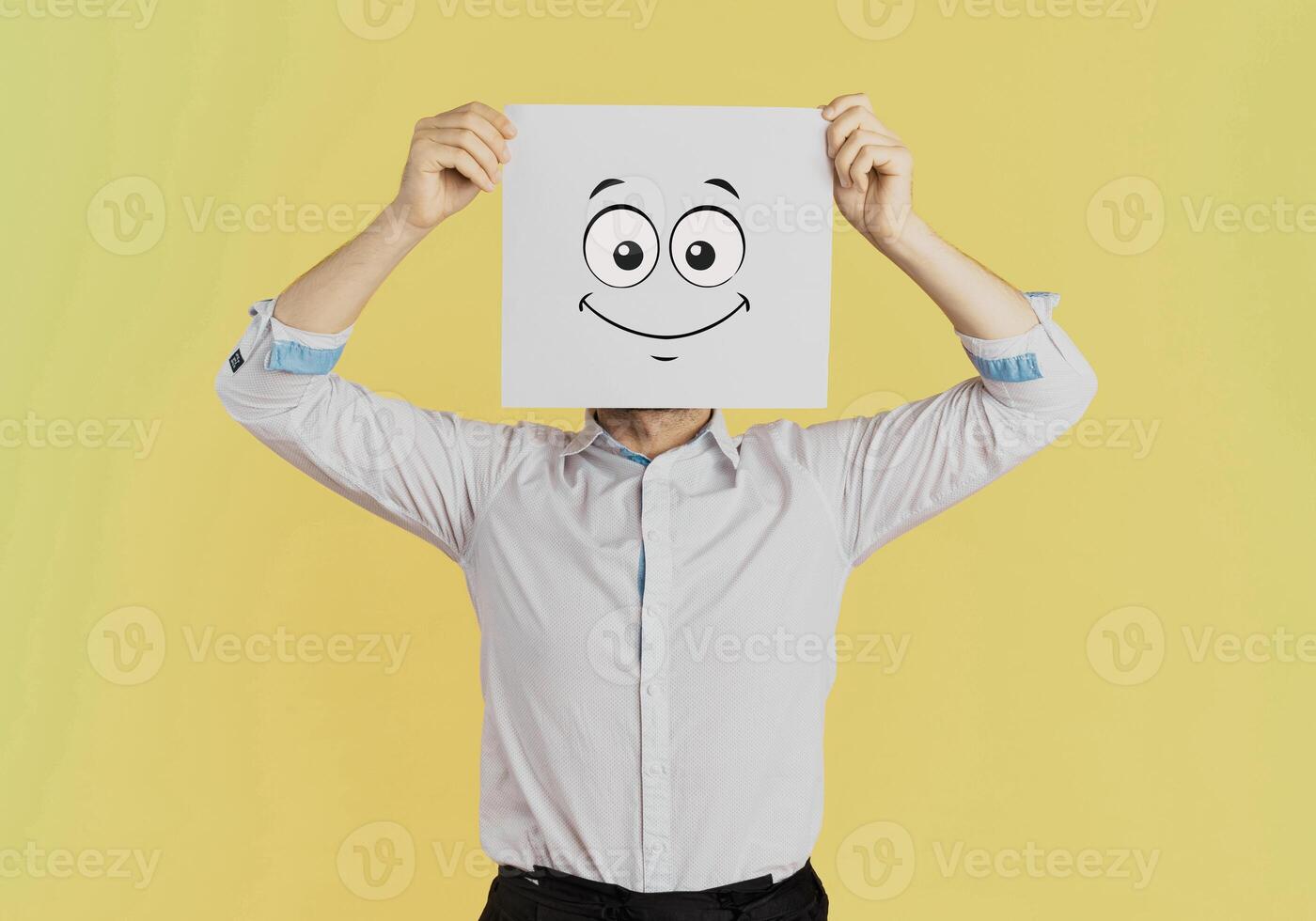 Young businessman holding white card with a happy face on it isolated on Yellow background photo