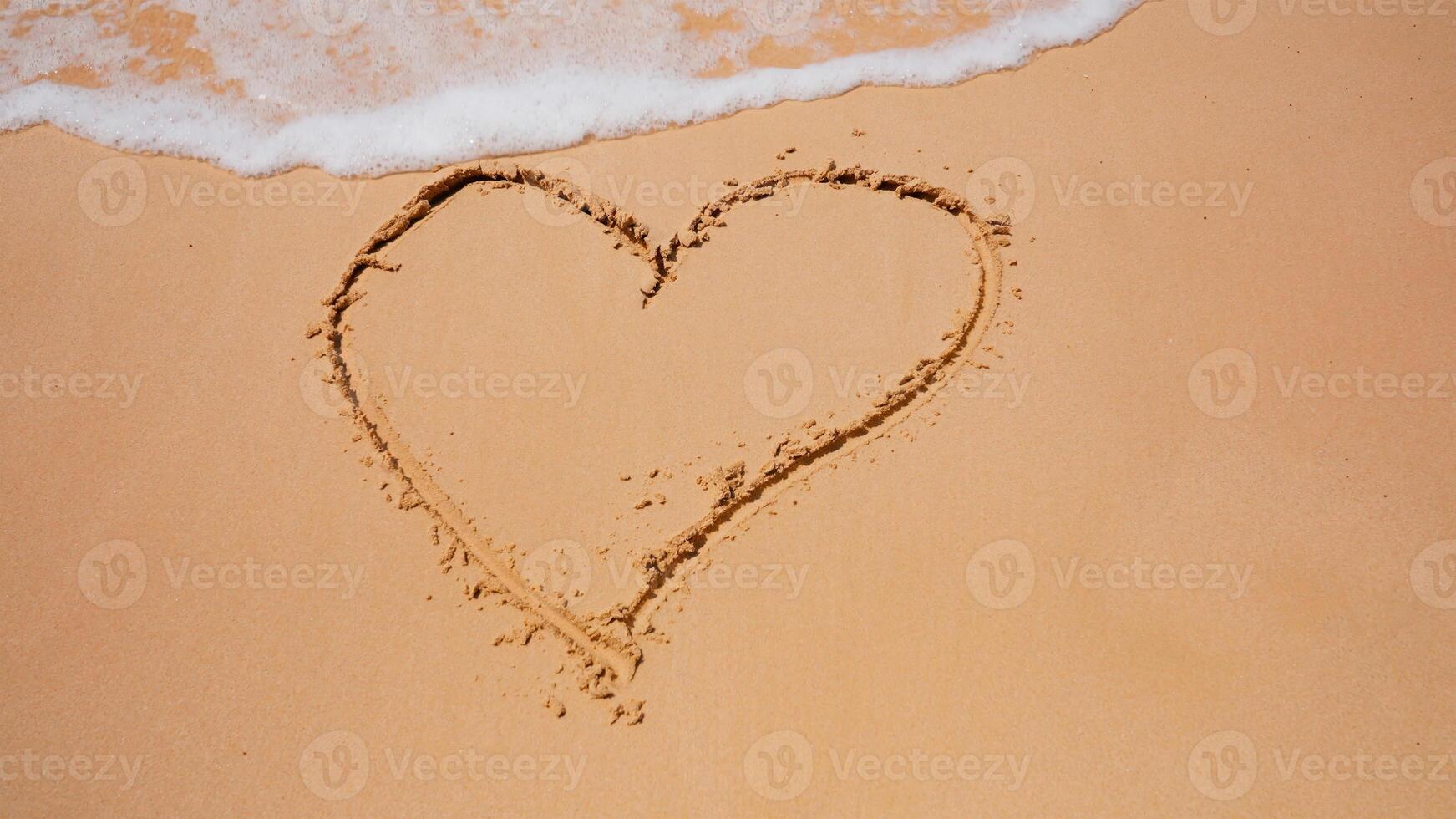 Drawing on the sand. Drawing heart. The sea shore is washed by a wave. photo